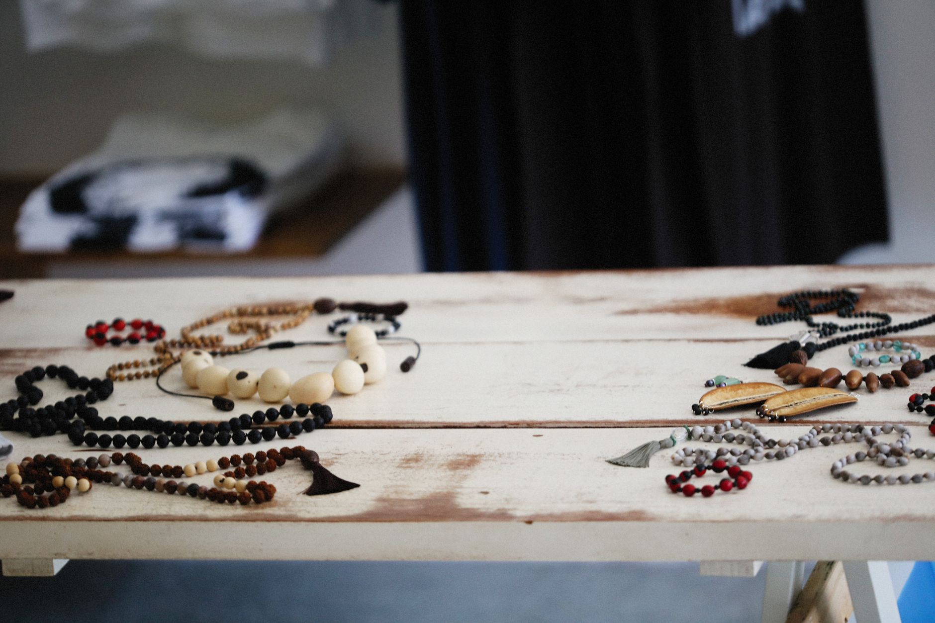 A diverse display of handcrafted wooden jewelry and beads on a rustic table indoors.