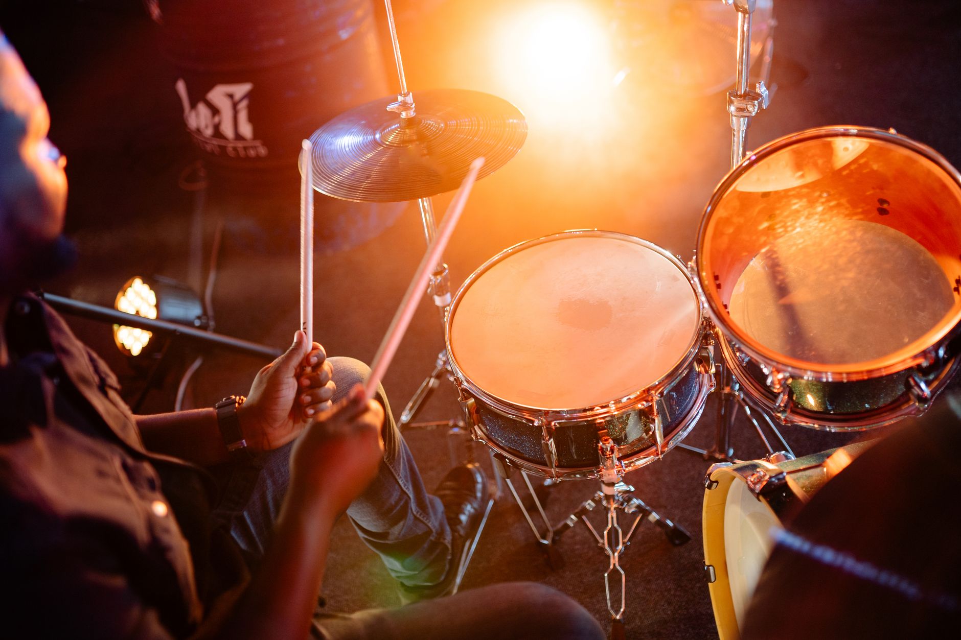 Vibrant scene of a drummer passionately playing a drum set under bright stage lights.