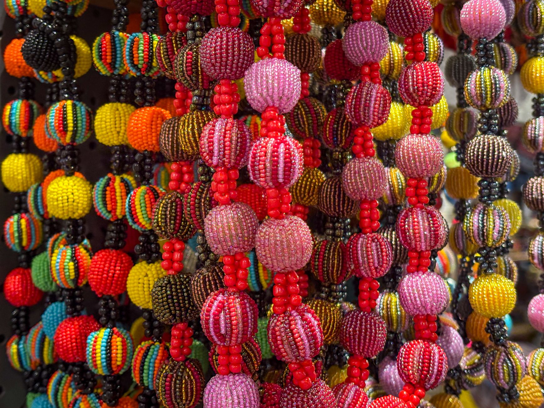 Vibrant handcrafted beaded necklaces displayed at a market stall, showcasing artisanal craftsmanship and cultural diversity.