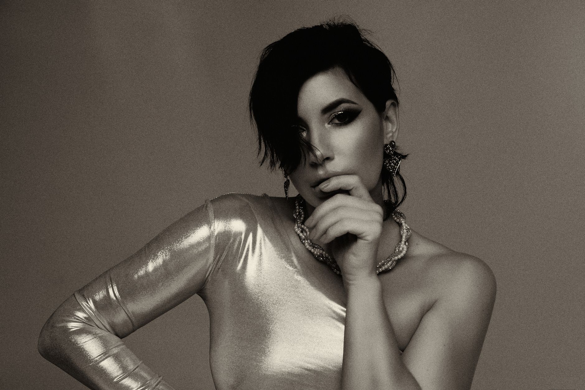 Stylish monochrome portrait of a woman in a metallic dress posing elegantly in a studio setting.