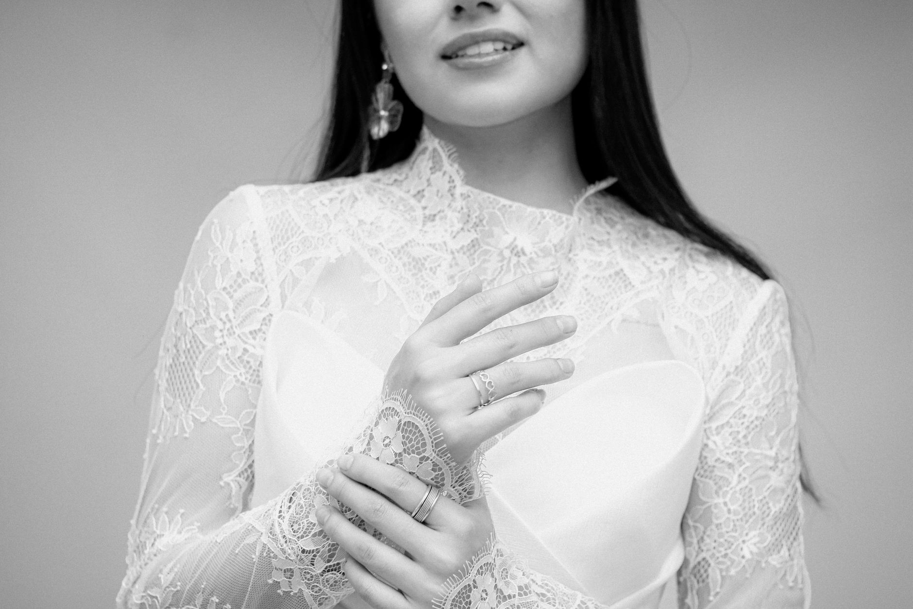 Black and white portrait of a bride in lace dress, focusing on delicate details.