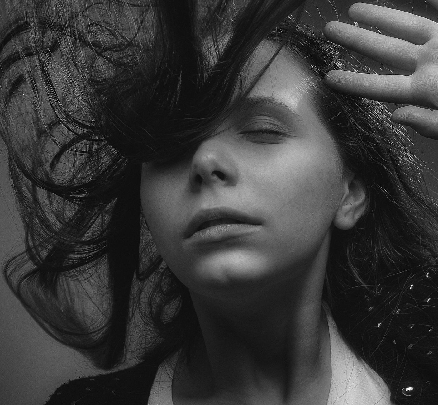 Black and white portrait of a woman with windblown hair, showcasing emotion and style.