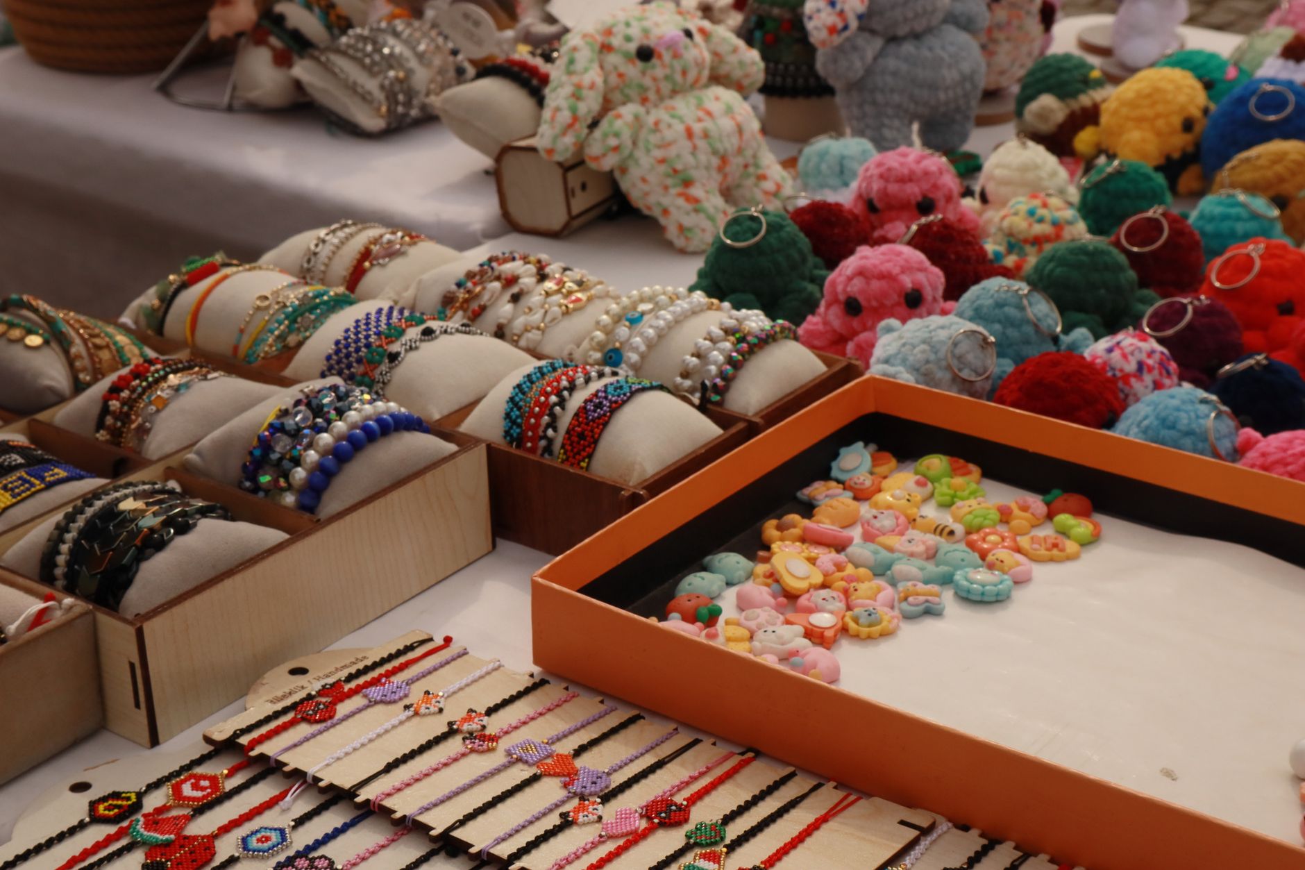 Vibrant display of handmade bracelets and crocheted keychains at a market stall.