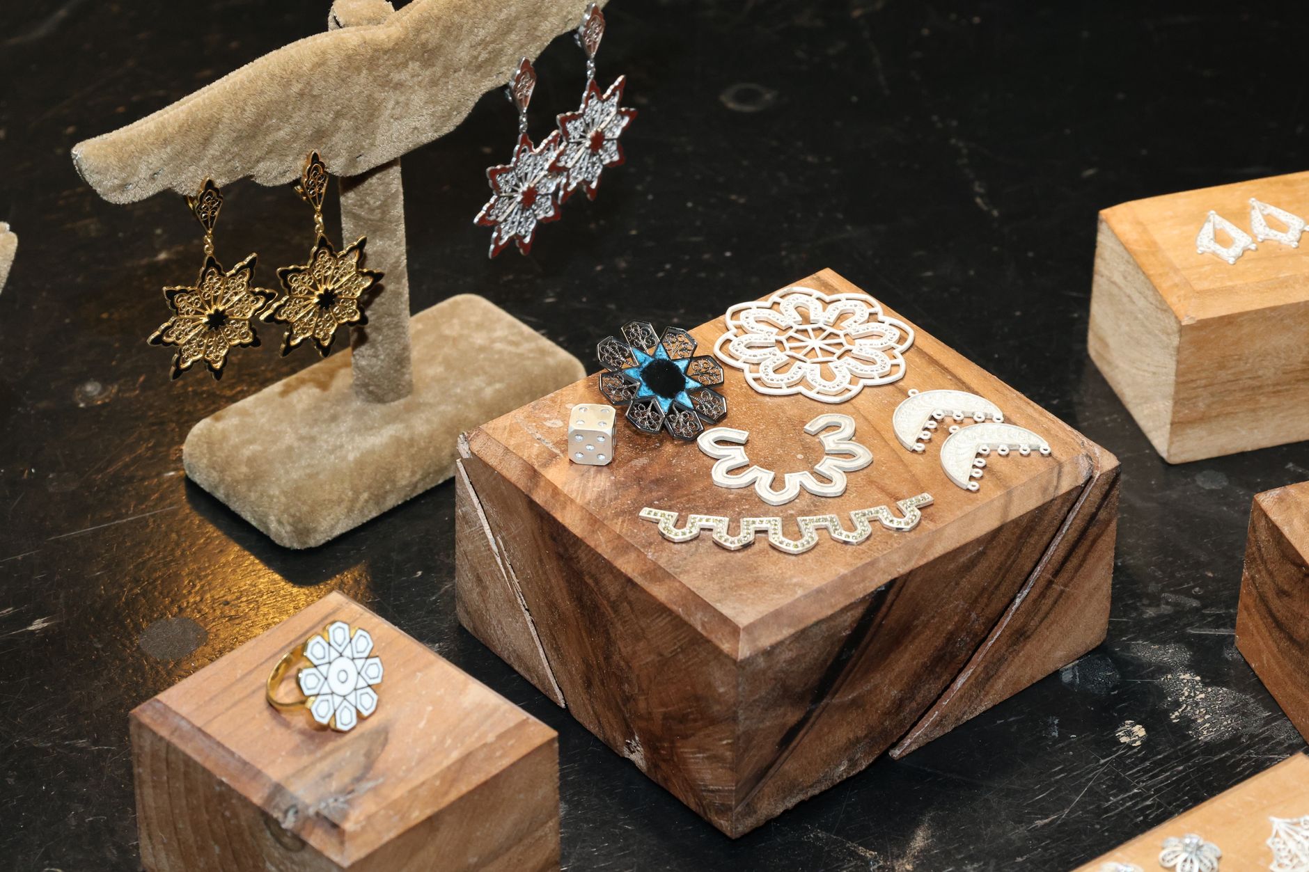 Display of elegant jewelry pieces on wooden blocks with intricate patterns and vibrant colors for stylish presentation.