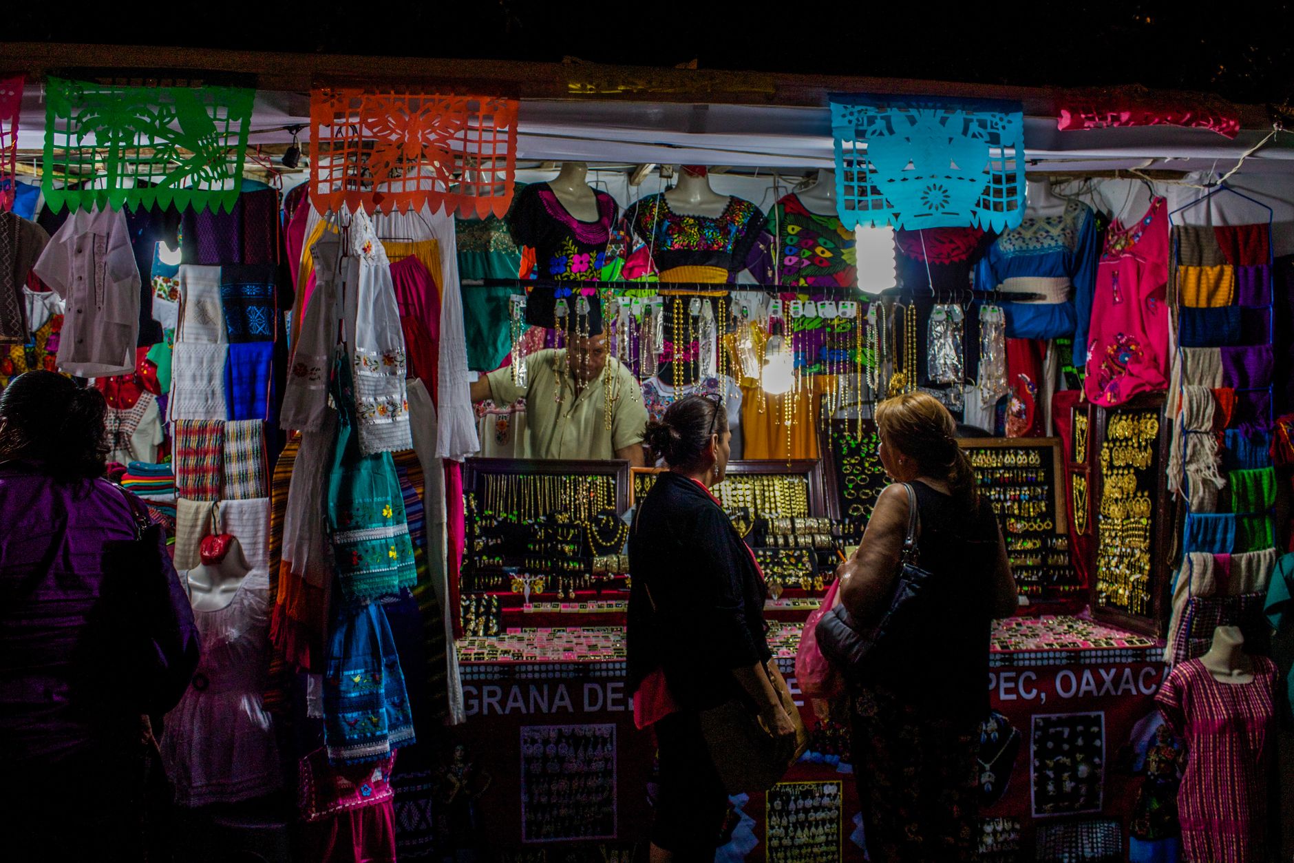 Colorful market stall in Oaxaca, Mexico, showcasing traditional crafts and jewelry at night.