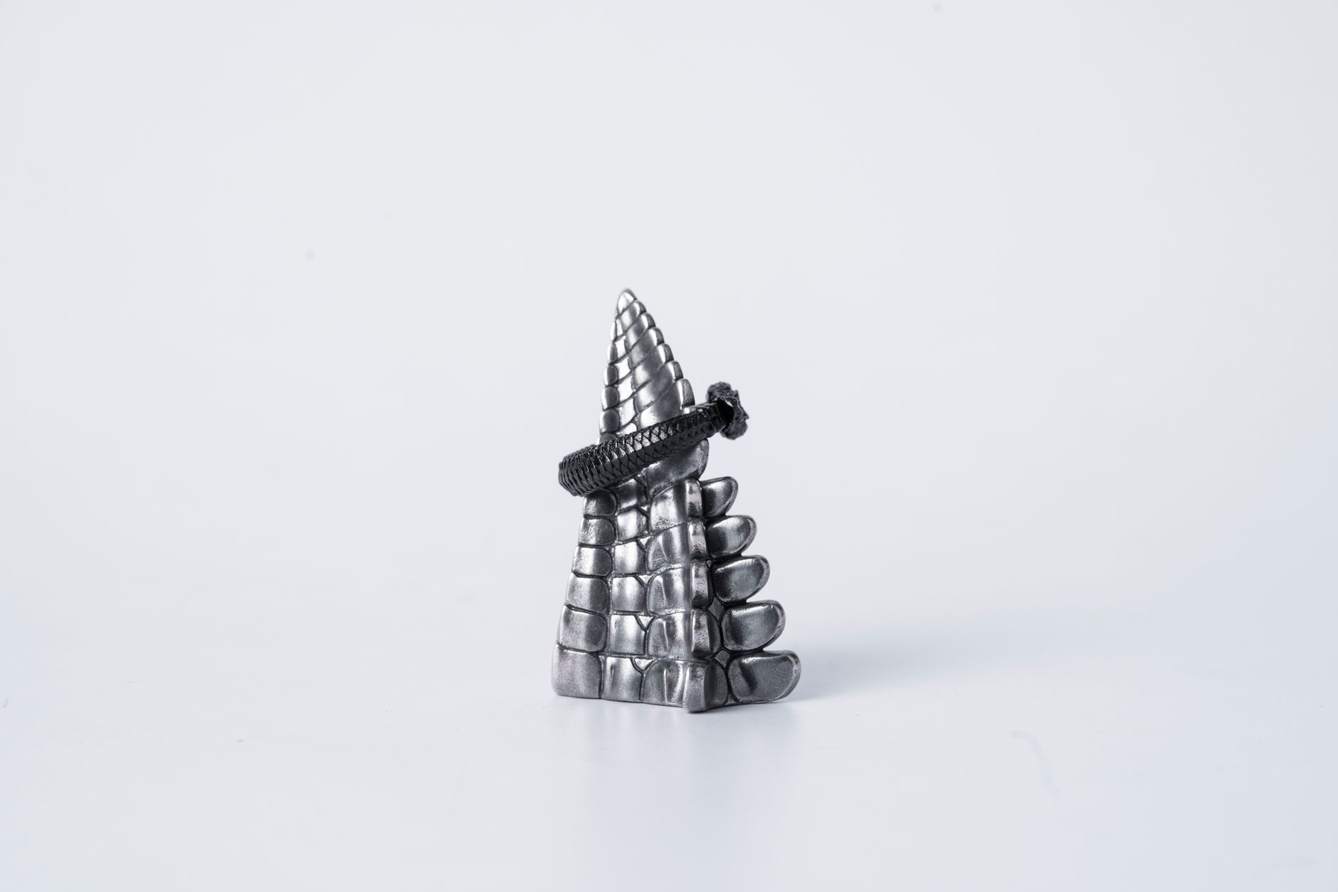 Close-up of a detailed silver ouroboros ring shaped like a snake tail on a white background.