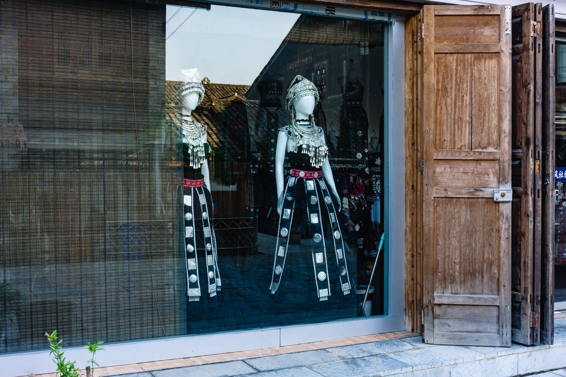 Traditional garments in a retail store window showcasing unique cultural attire.
