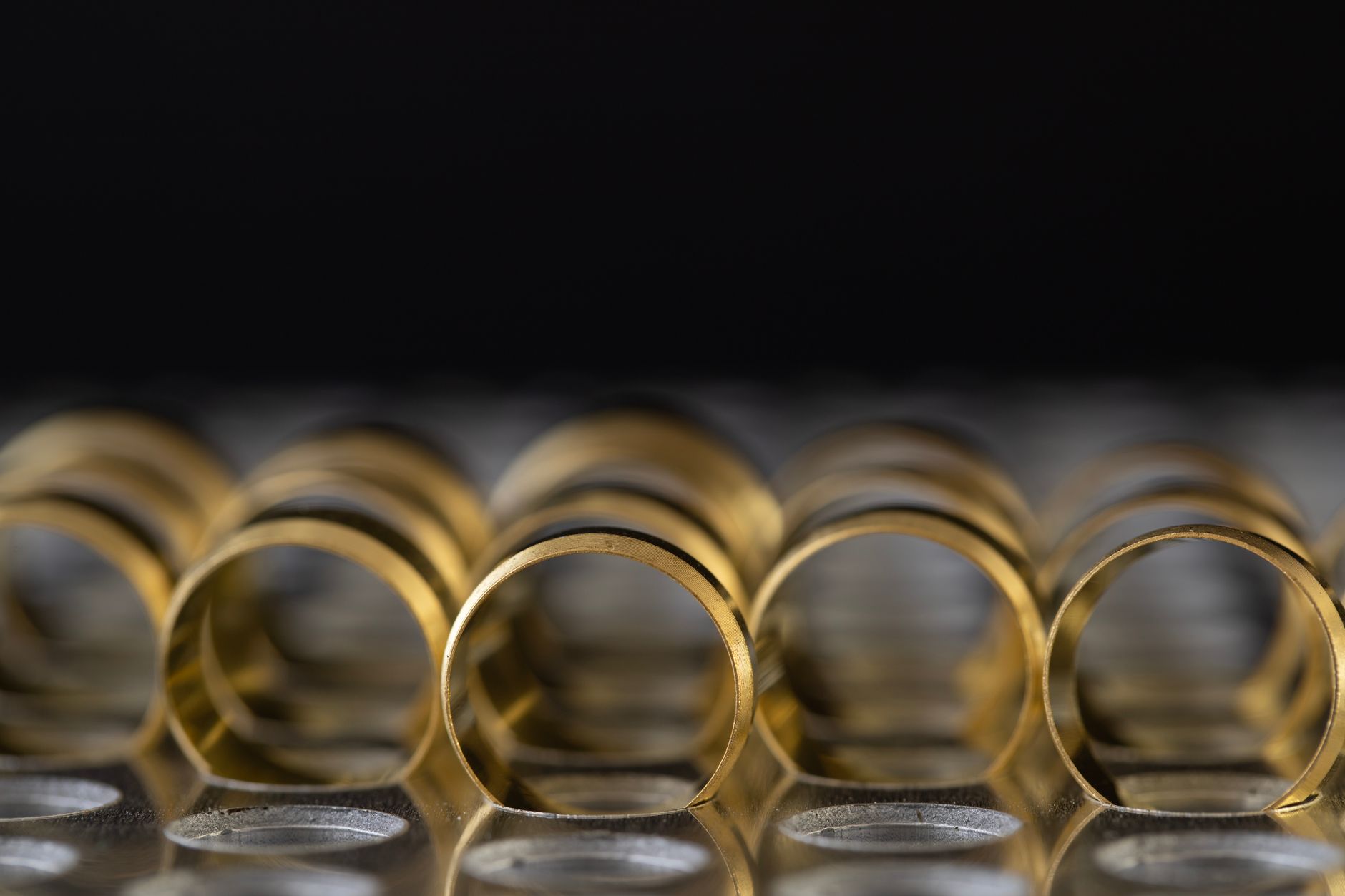 A detailed image of stacked golden rings with reflective surfaces on a dark background.