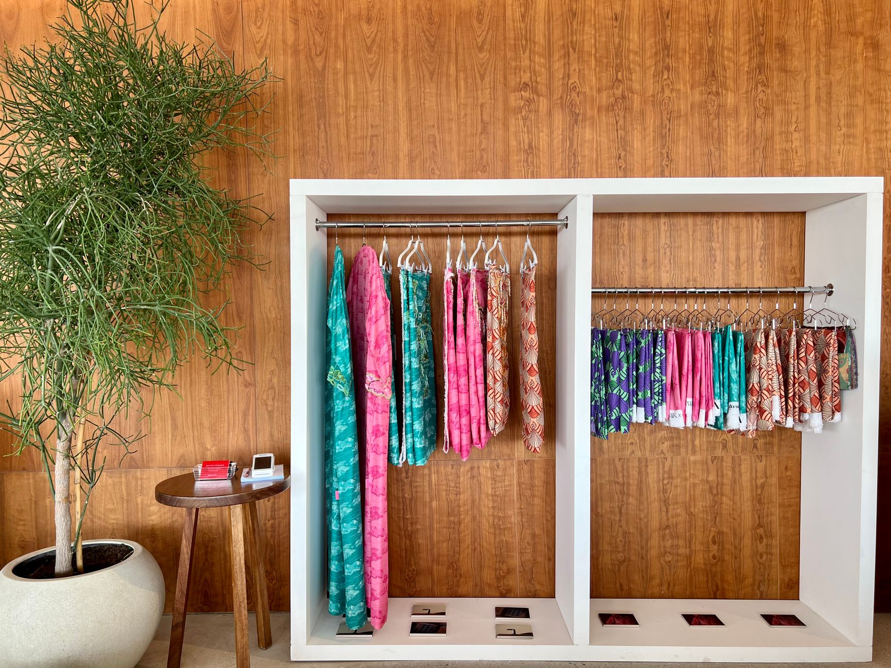 Vibrant dresses showcased in an Abu Dhabi boutique against a wooden backdrop.