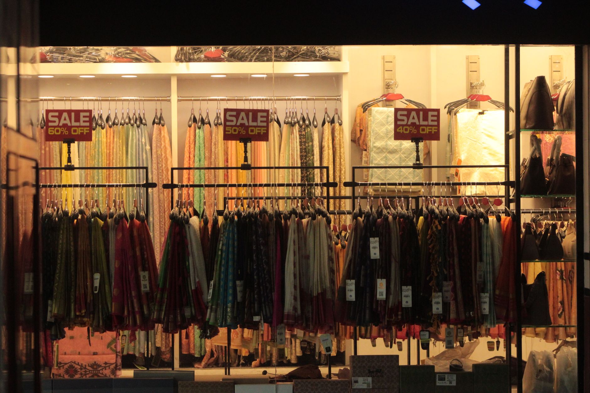 Vibrant clothing store interior showcasing colorful fabrics with sale discount signs.