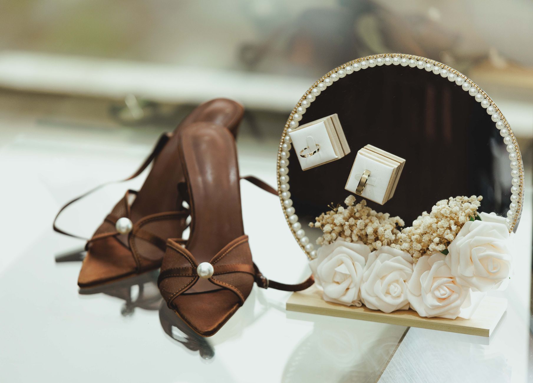 Close-up of bridal accessories featuring brown shoes, jewelry, and floral decorations, perfect for weddings.