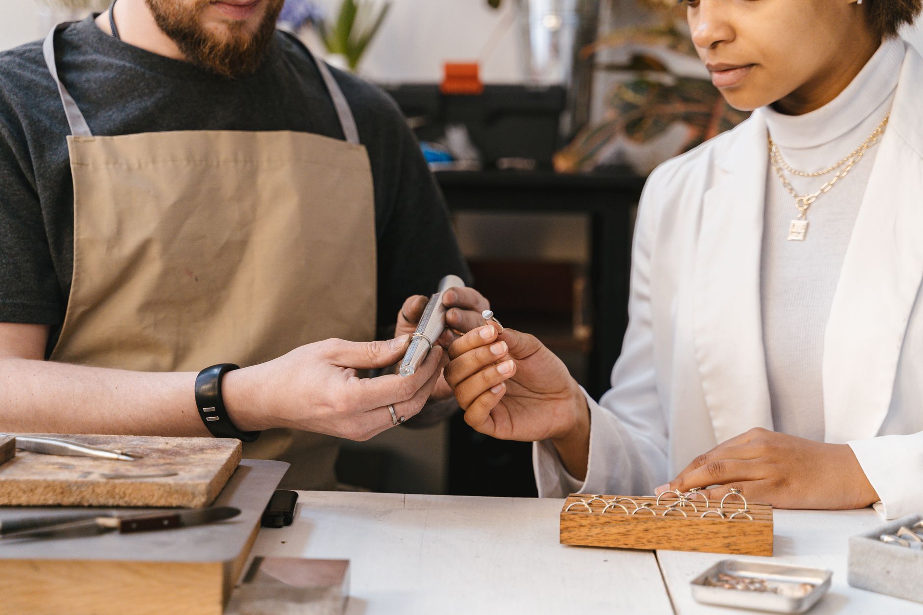 Two artisans collaborate in a workshop, focusing on jewelry design and craftsmanship.