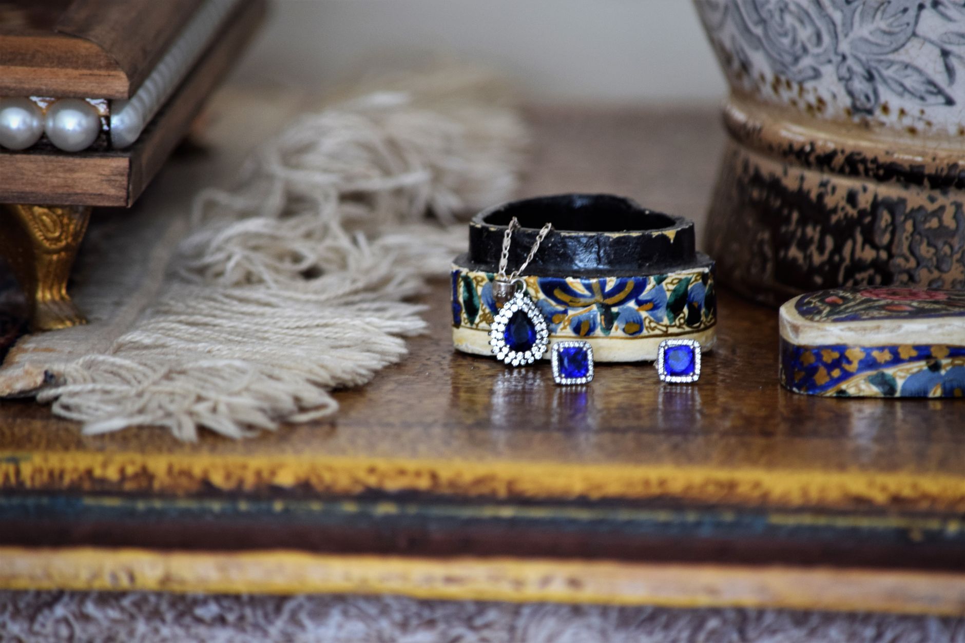 Close-up of elegant jewelry including earrings and pendant on a rustic table setting.