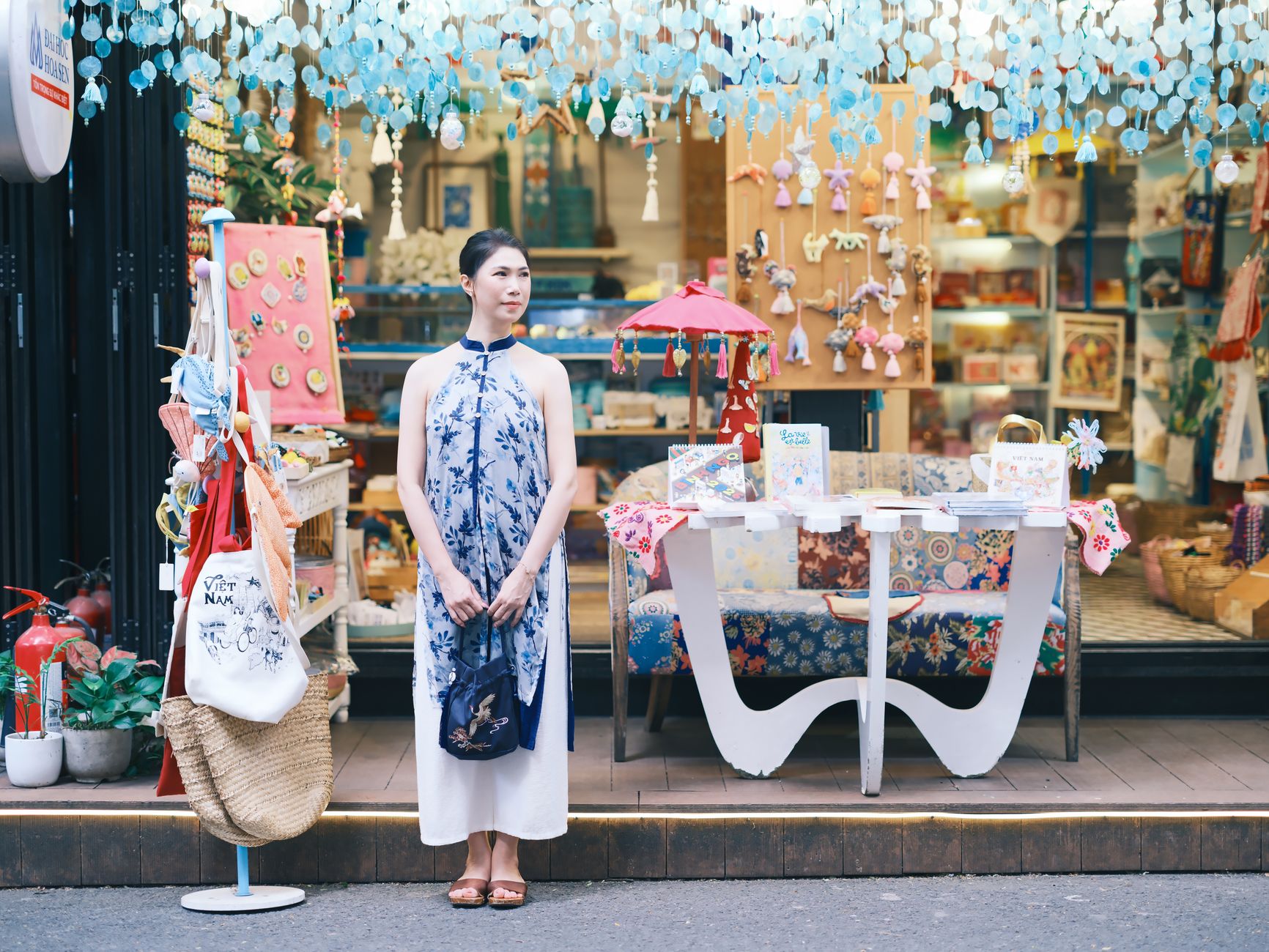 Woman in traditional dress standing in front of a colorful boutique, showcasing ethnic crafts.