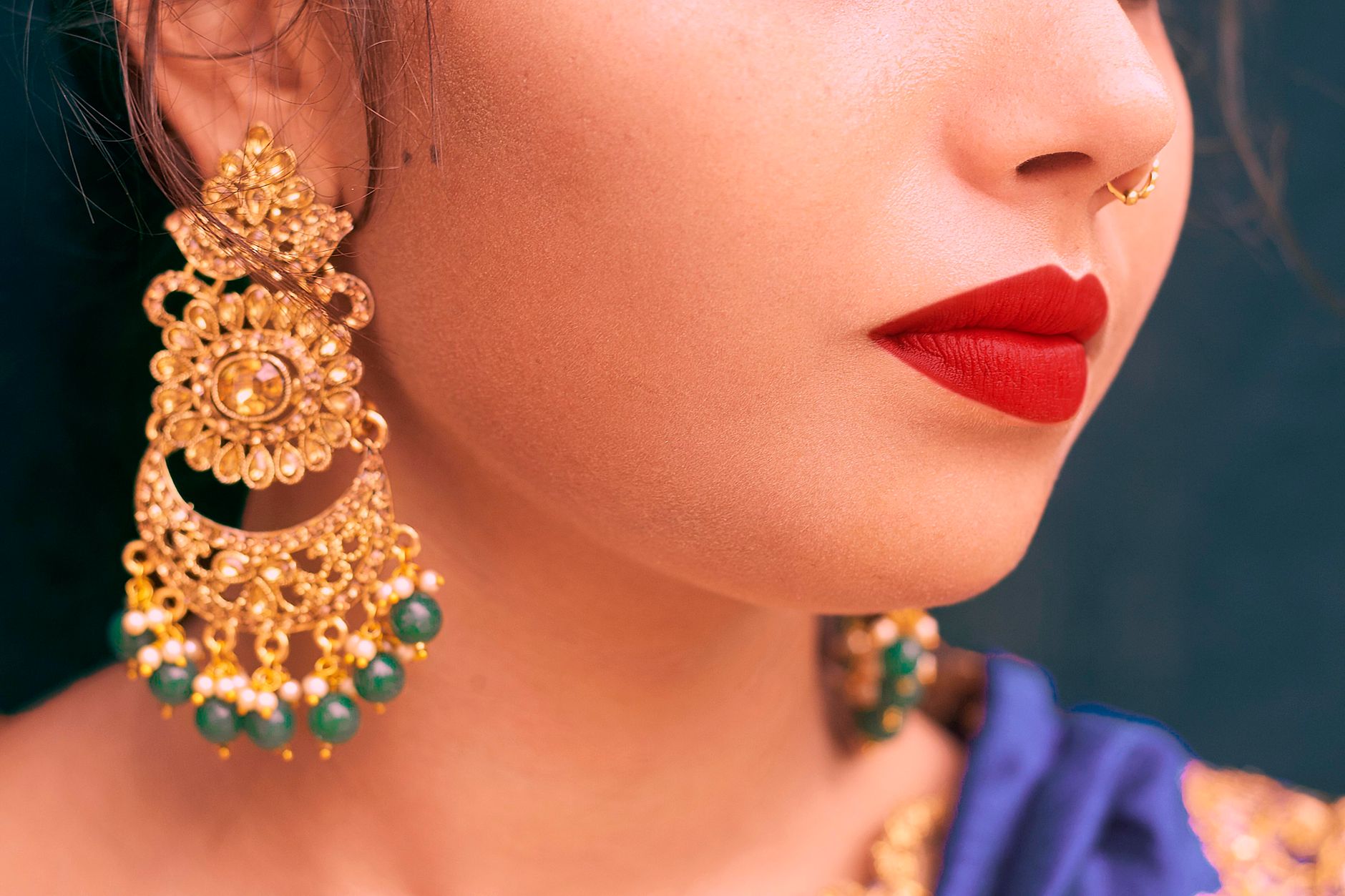 Close-up of traditional Indian earrings and nose ring on a woman with red lips. Ideal for cultural themes.
