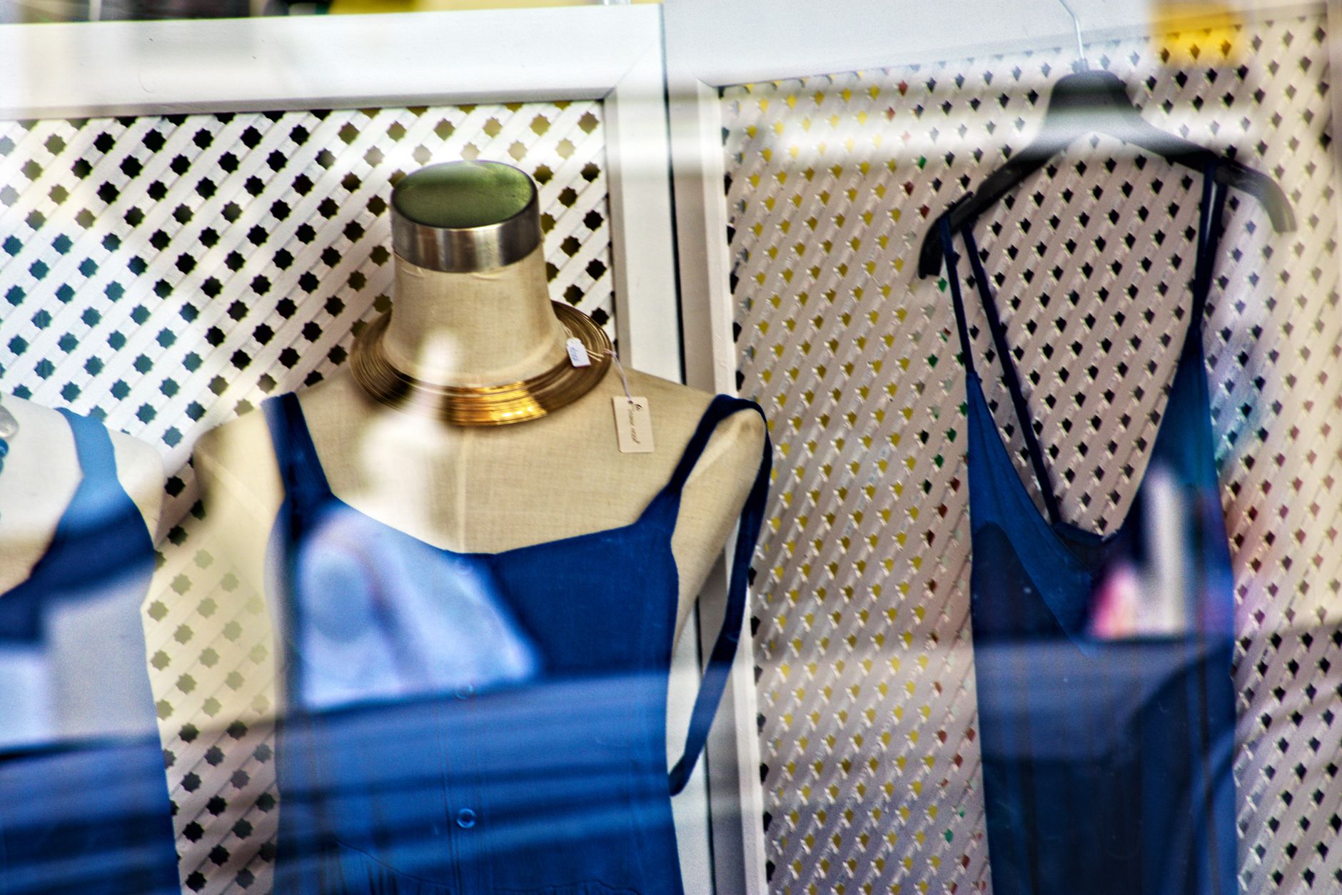 Stylish blue dresses on mannequins in a boutique window display with fashionable accessories.