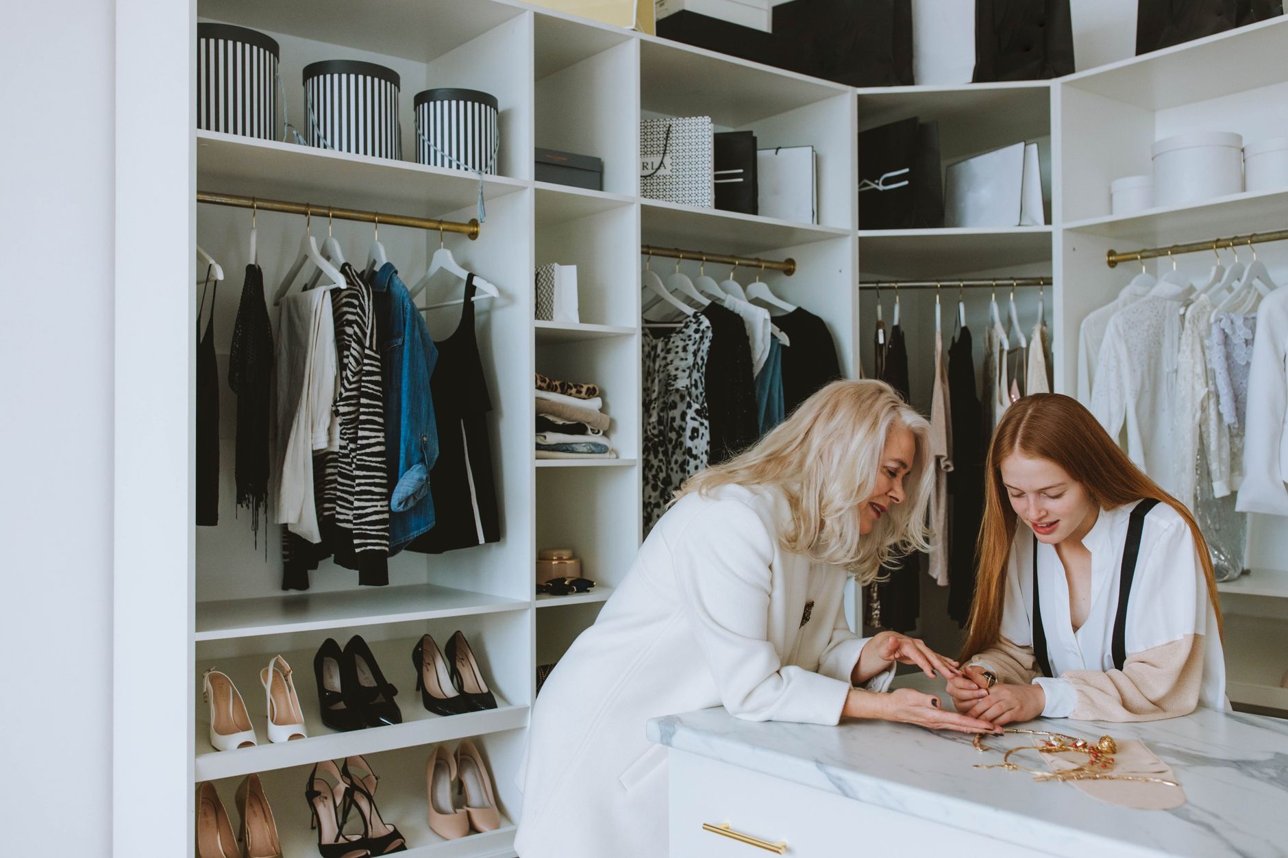 Senior and young woman enjoying a fashion consultation in a stylish boutique wardrobe setting.