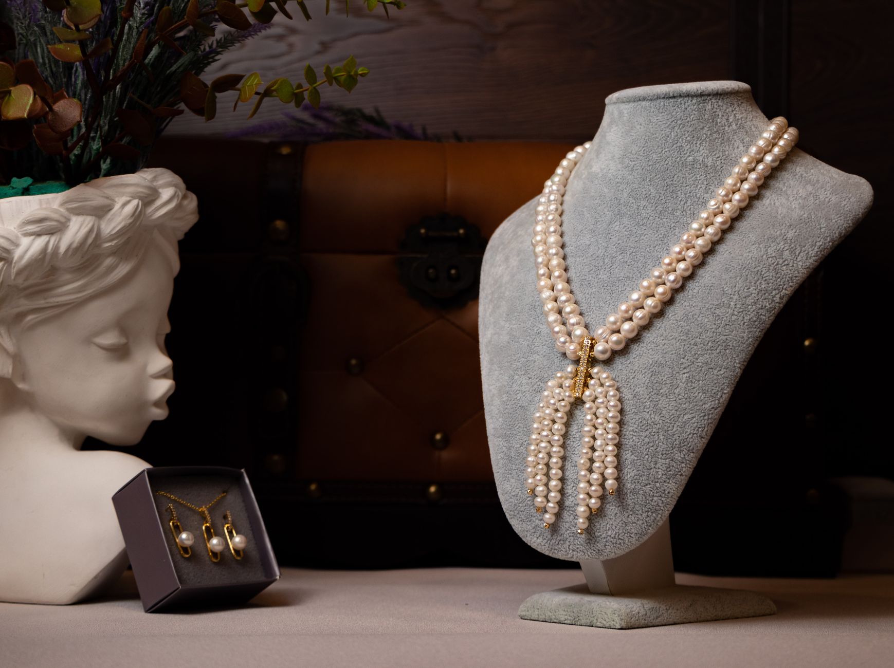 Luxurious pearl necklace displayed elegantly on a bust alongside pearl earrings.