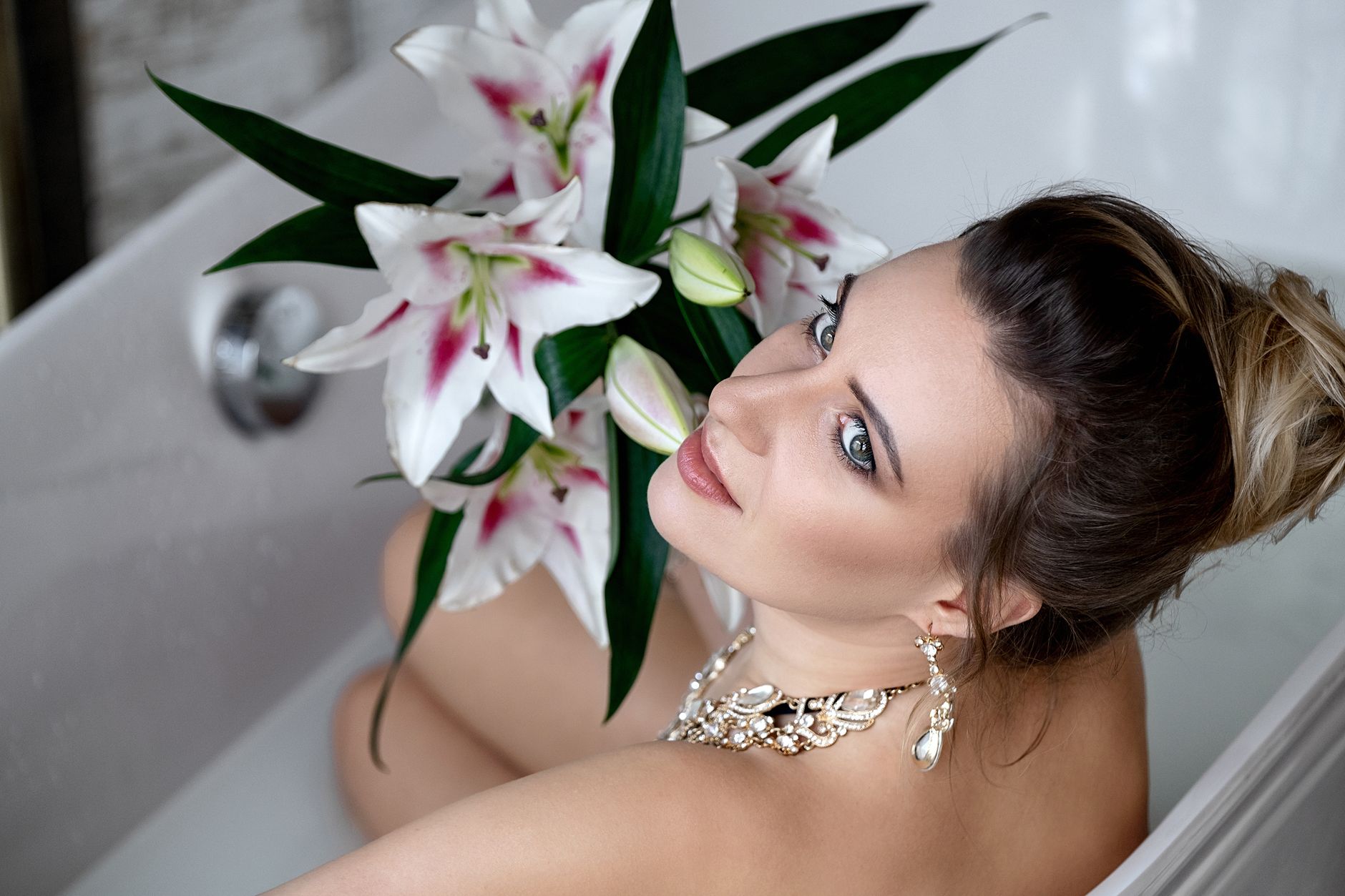 A beautiful woman in a luxurious bathtub holding a bouquet of lilies, highlighting elegance and relaxation.