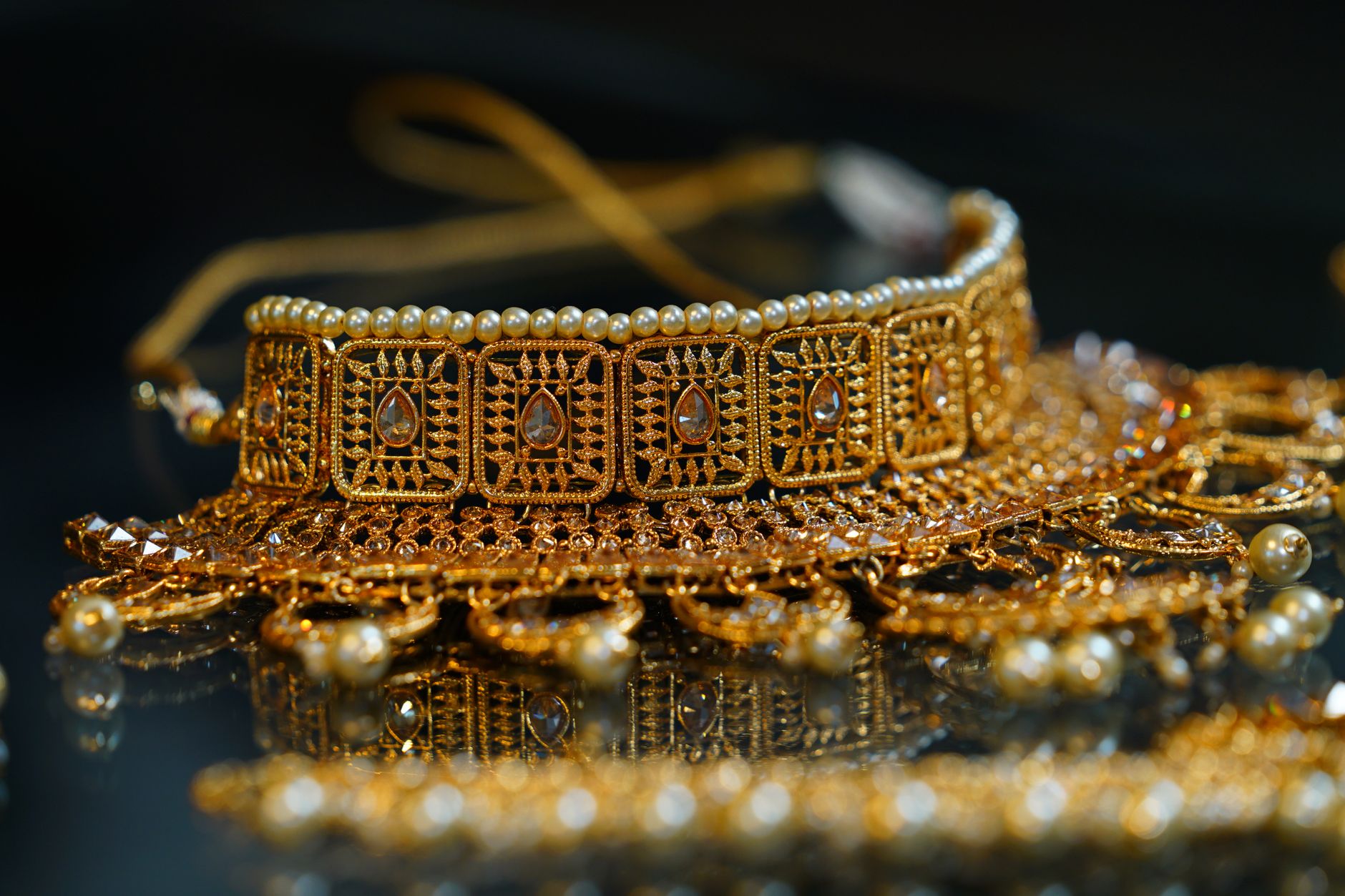 Stylish golden bracelet or necklace in oriental style decorated with pearls and crystals placed on black surface