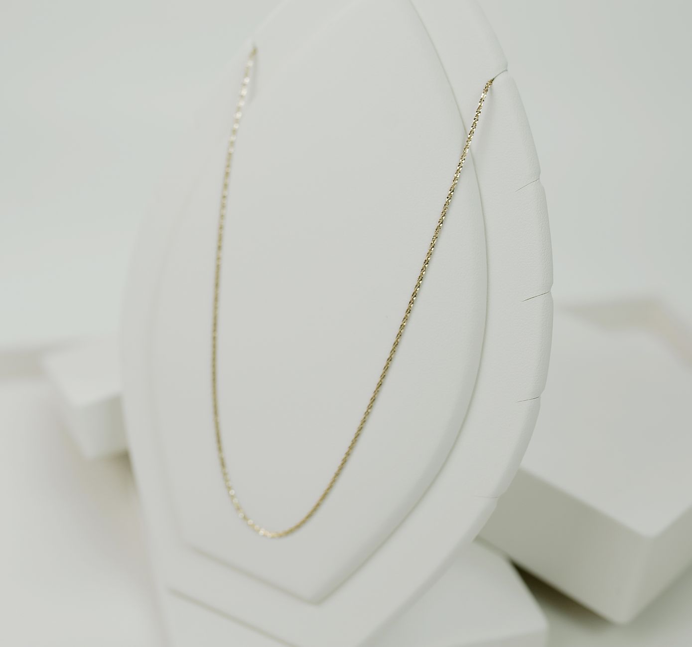 Close-up of a delicate gold necklace displayed elegantly on a white stand, perfect for fashion and jewelry lovers.