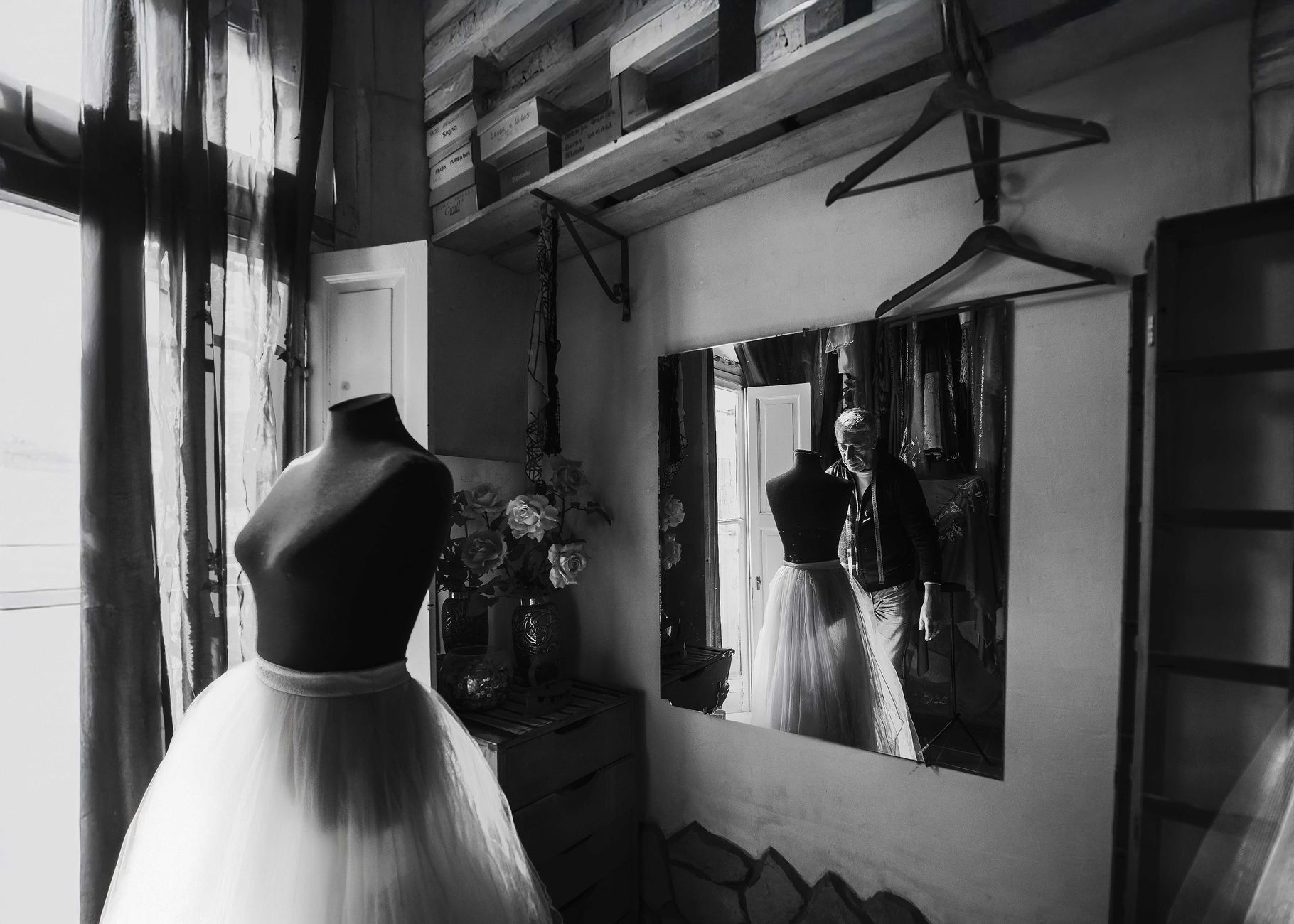 Black and white image of a mannequin dressed in a skirt inside a stylish fashion boutique with mirror reflection.