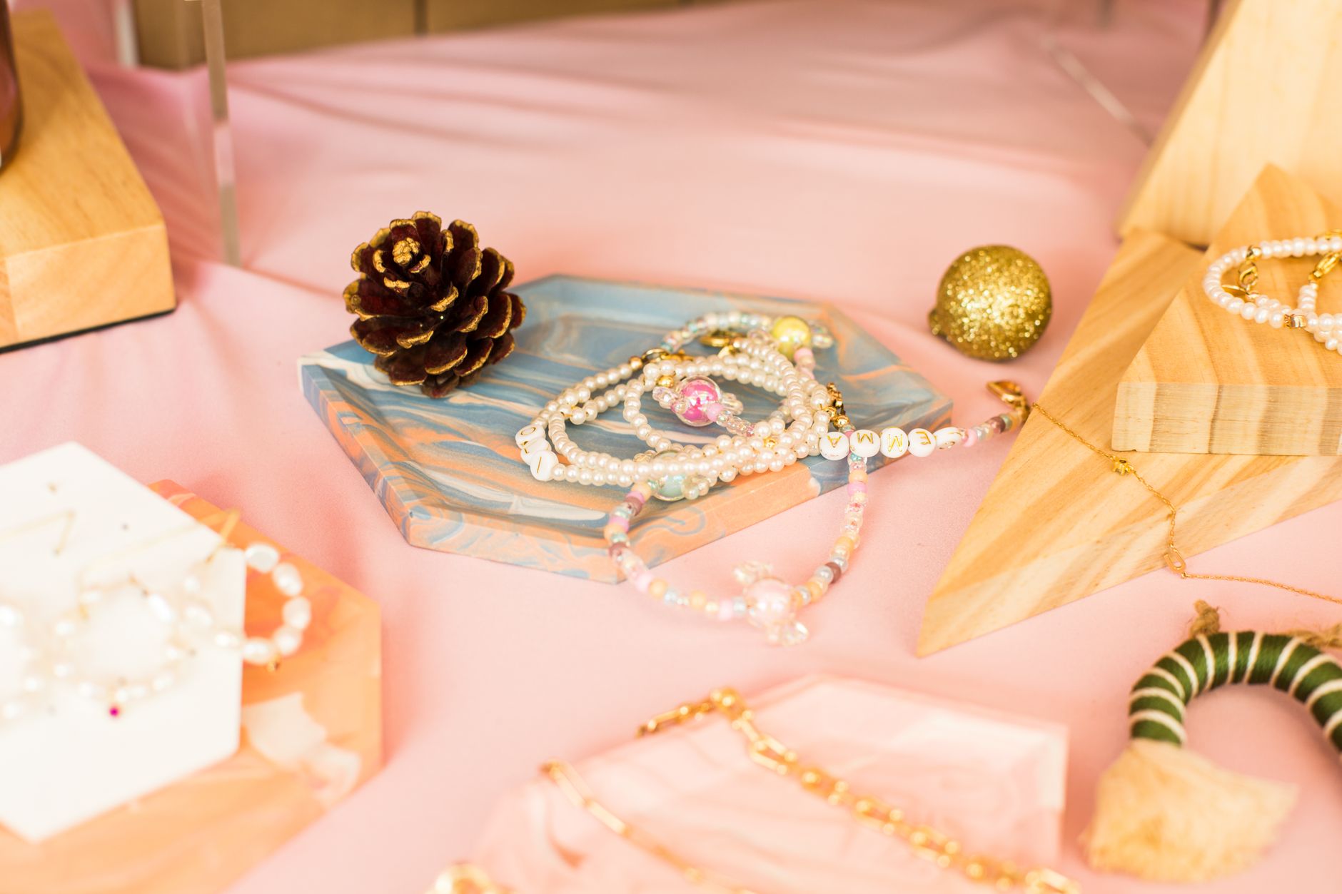 Chic arrangement of luxury jewelry on a pastel pink surface featuring pearls and decorative items.