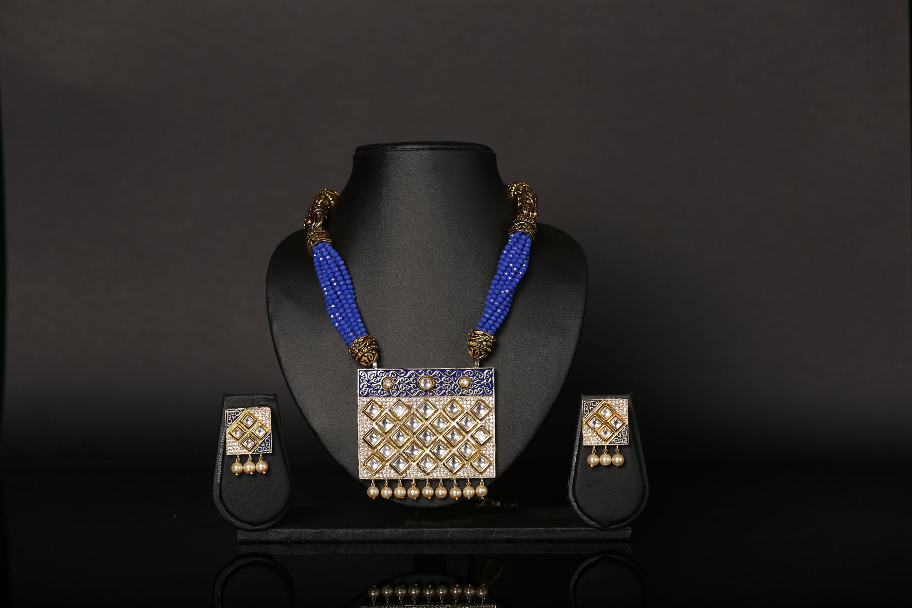 Luxury blue beaded necklace and earrings set displayed on a black background, showcasing elegance.
