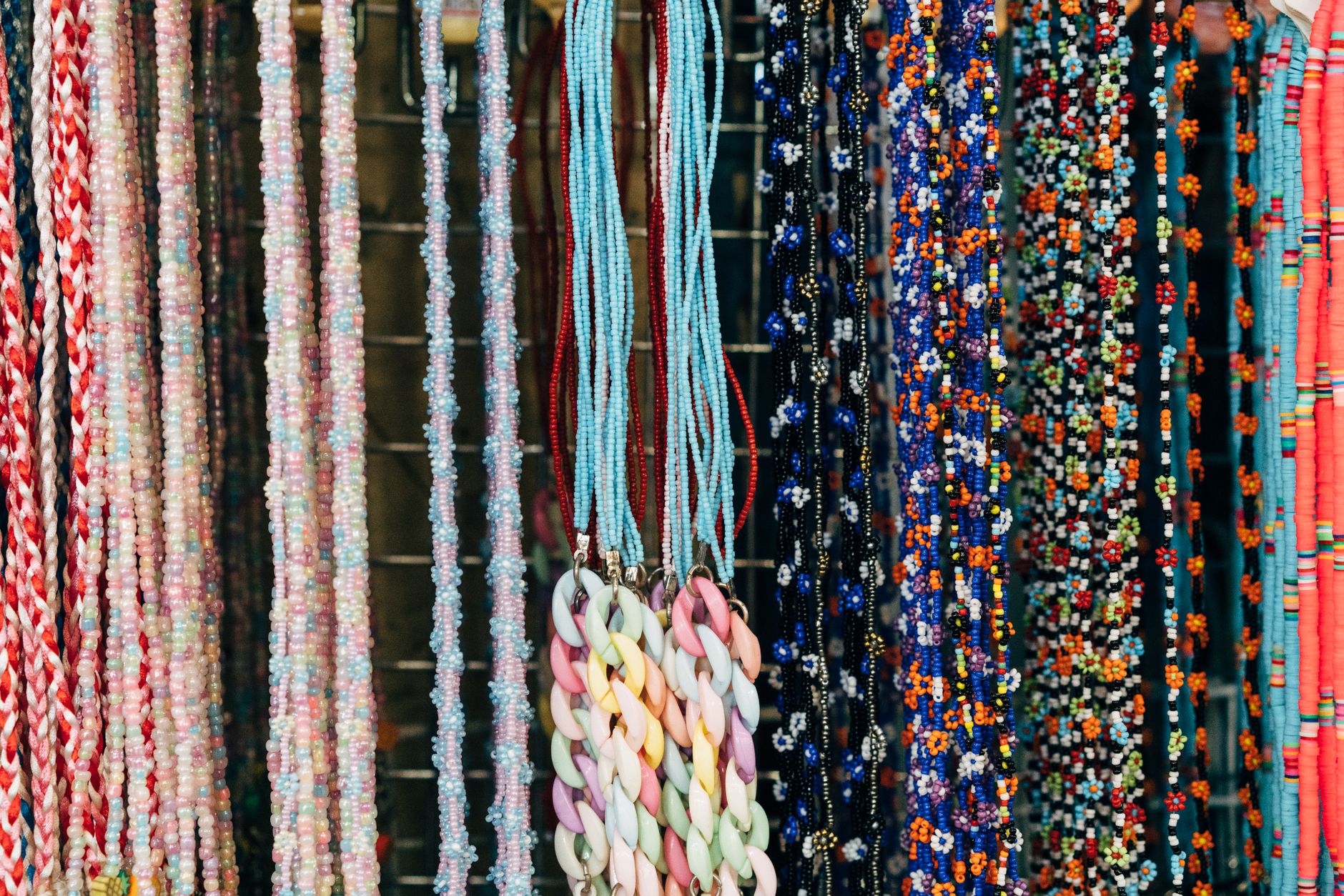 A vibrant display of various multicolored bead necklaces for sale at a market.