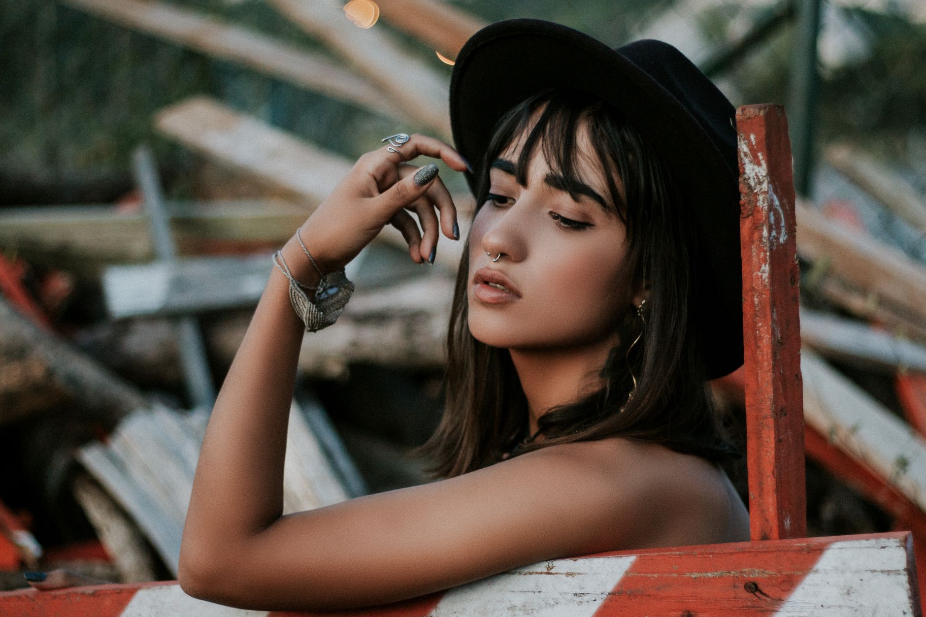 A serene portrait of a woman wearing a hat and nose ring, captured outdoors.