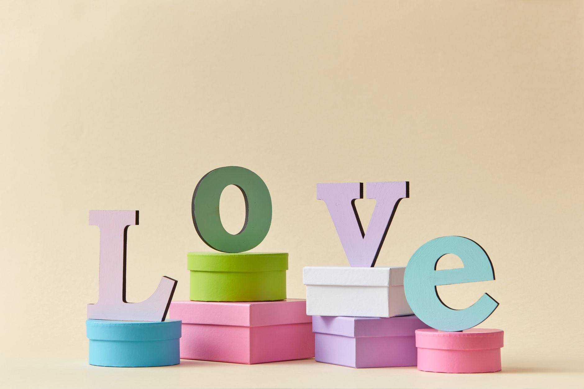 Pastel colored 'LOVE' letters placed on stacked gift boxes, creating a romantic and vibrant art piece.