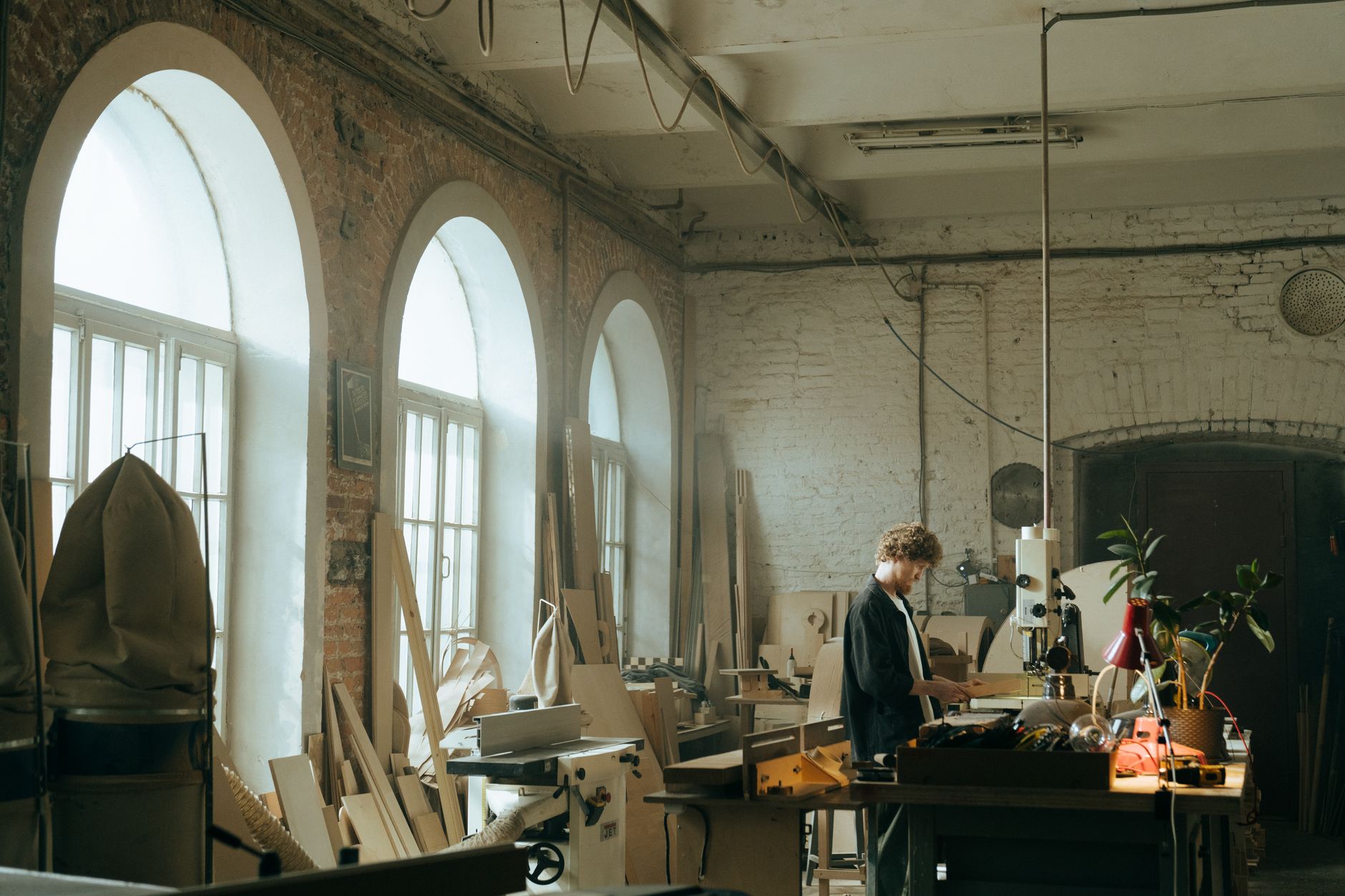 A skilled craftsman focused on woodworking in a rustic, well-lit workshop with arched windows.
