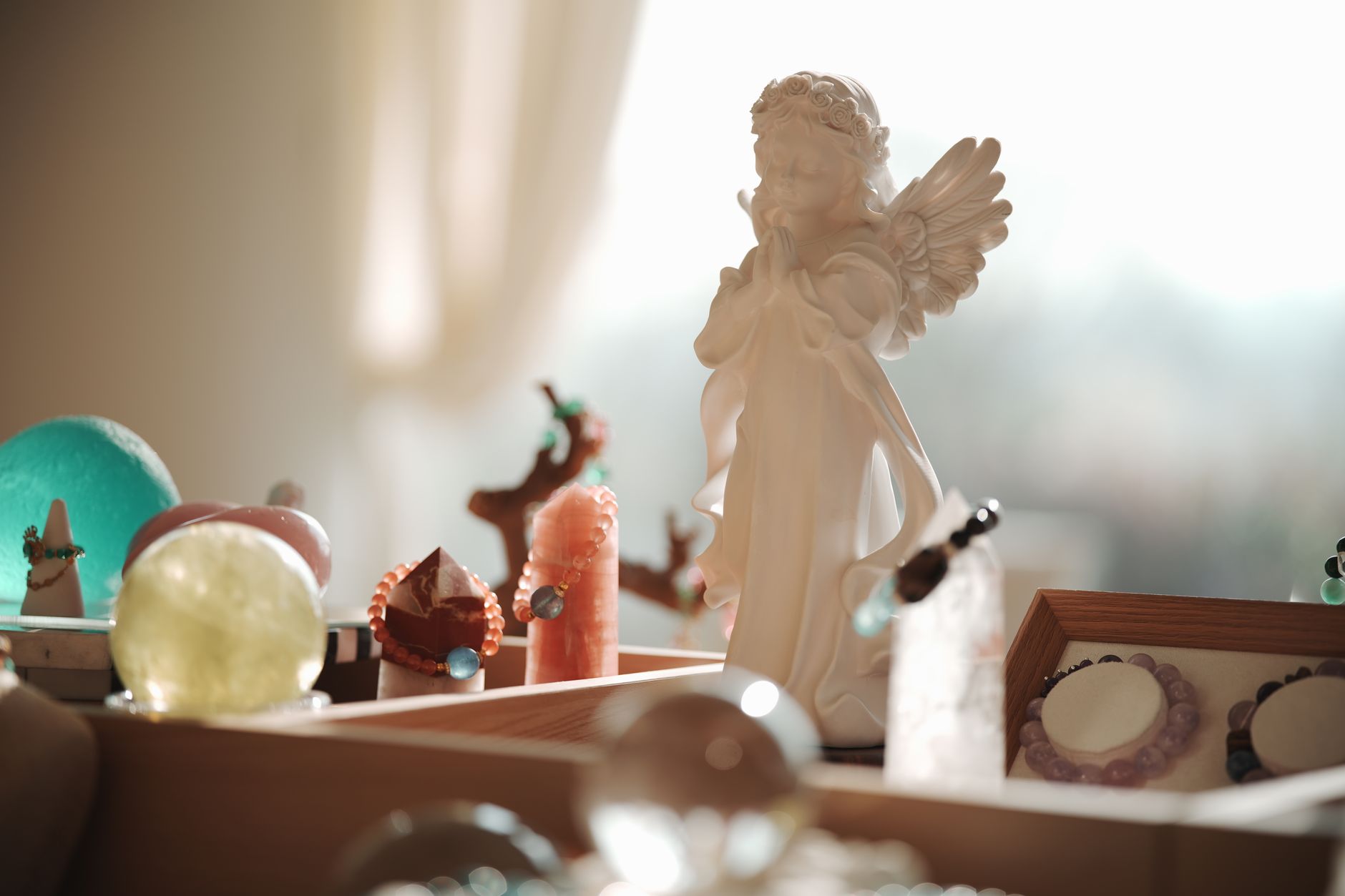 Elegant angel figurine with crystals and bracelets in soft morning light.