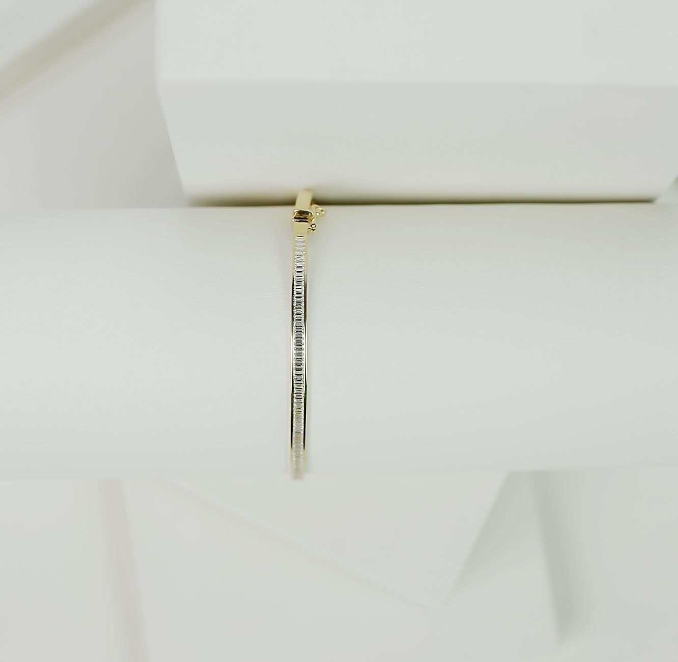 Sleek gold bracelet on white geometric background, showcasing luxury and simplicity.