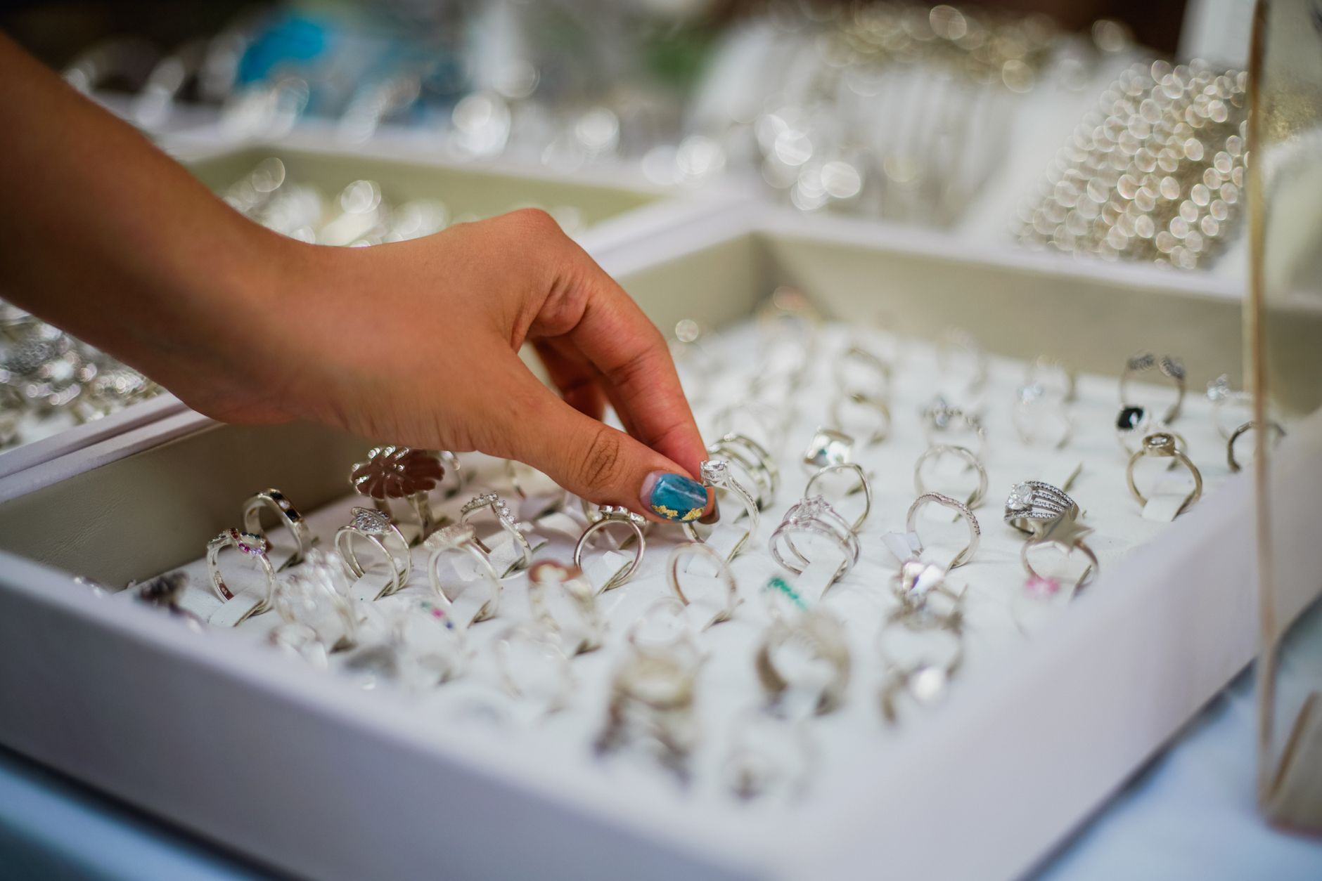 A woman's hand delicately picking a ring from a display of elegant jewelry.