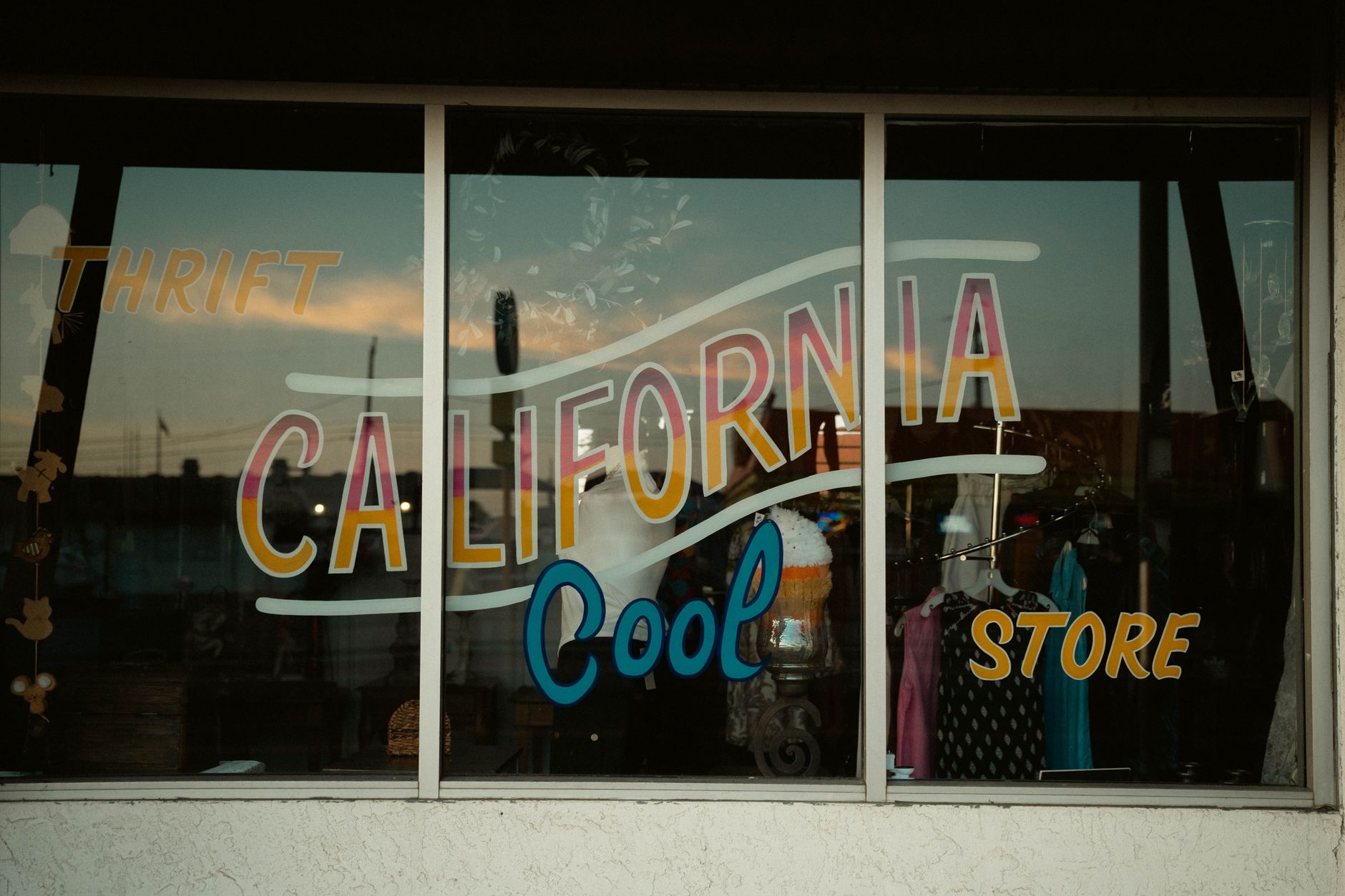 Vintage shop window with retro California thrift store signage and colorful display.