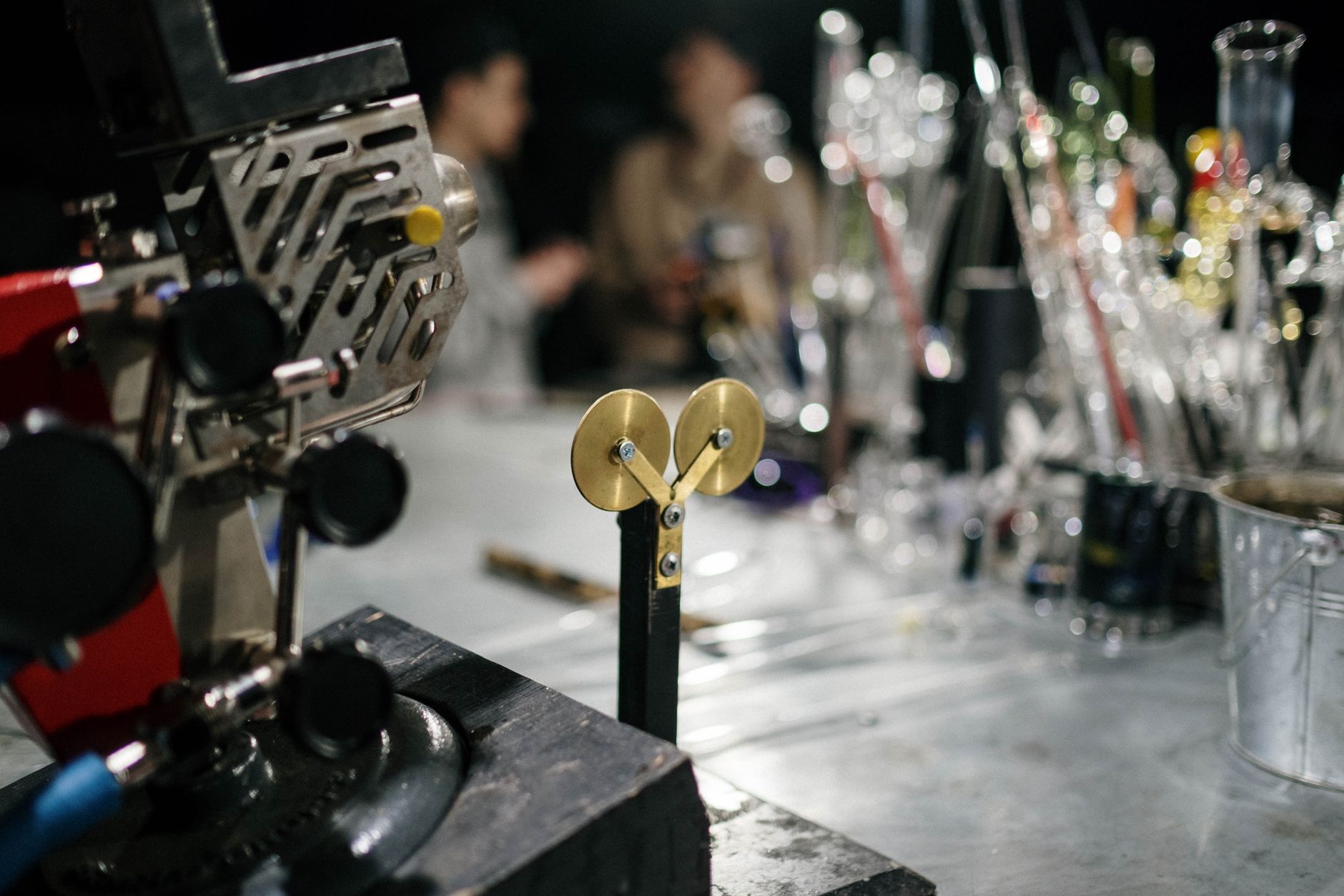 Close-up of machinery and glassware in an industrial workshop setting, featuring tools and equipment.