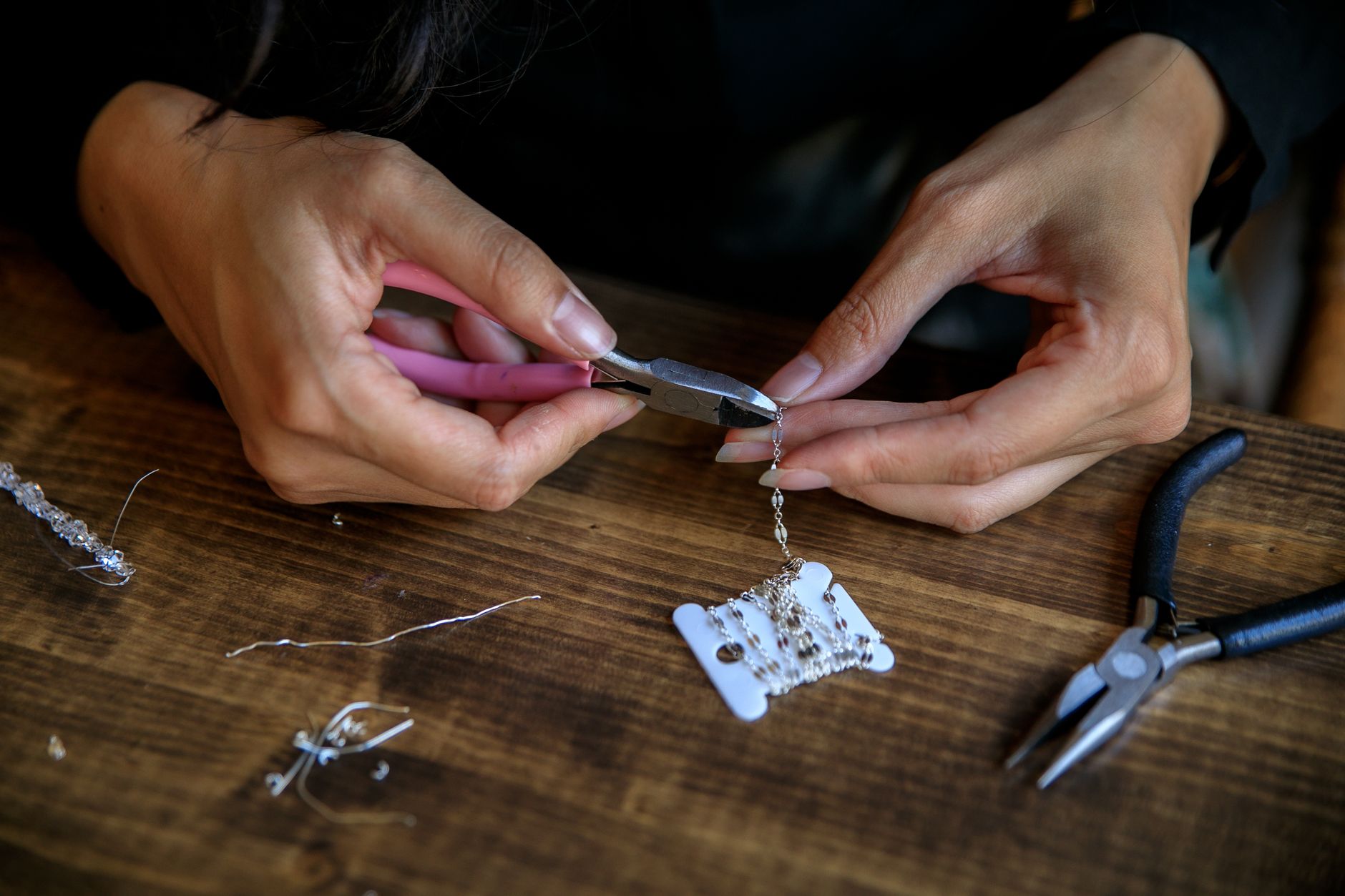 Detailed view of hands crafting jewelry using pliers, showcasing creativity and craftsmanship.