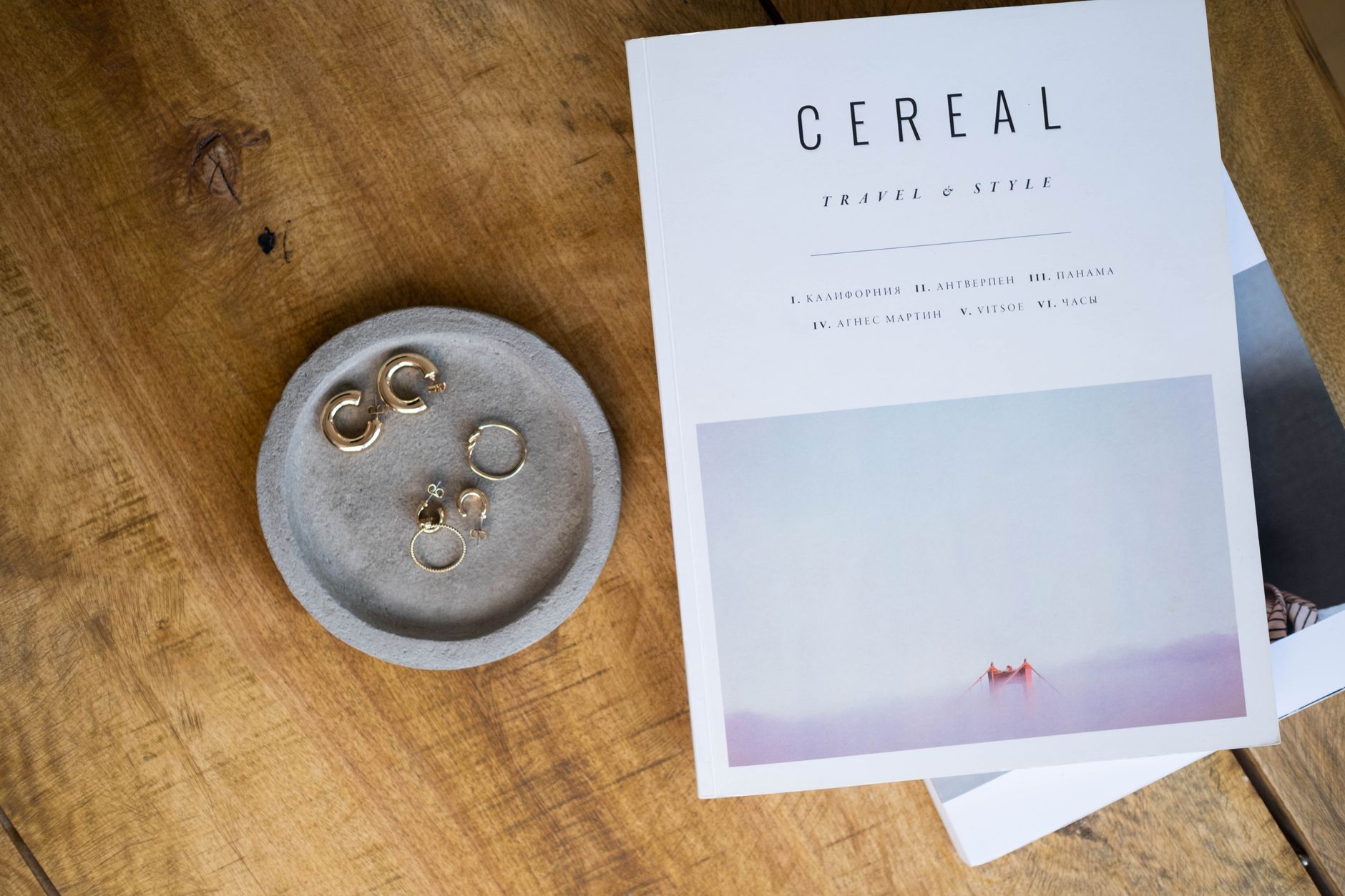Top view of elegant jewelry next to a lifestyle magazine on a wooden surface.