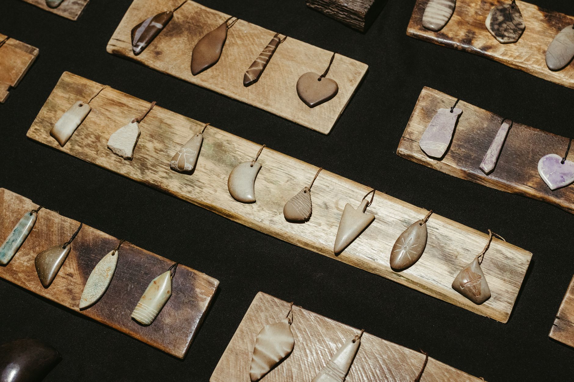 A collection of rustic stone pendants elegantly displayed on wooden boards, showcasing artisanal craftsmanship.