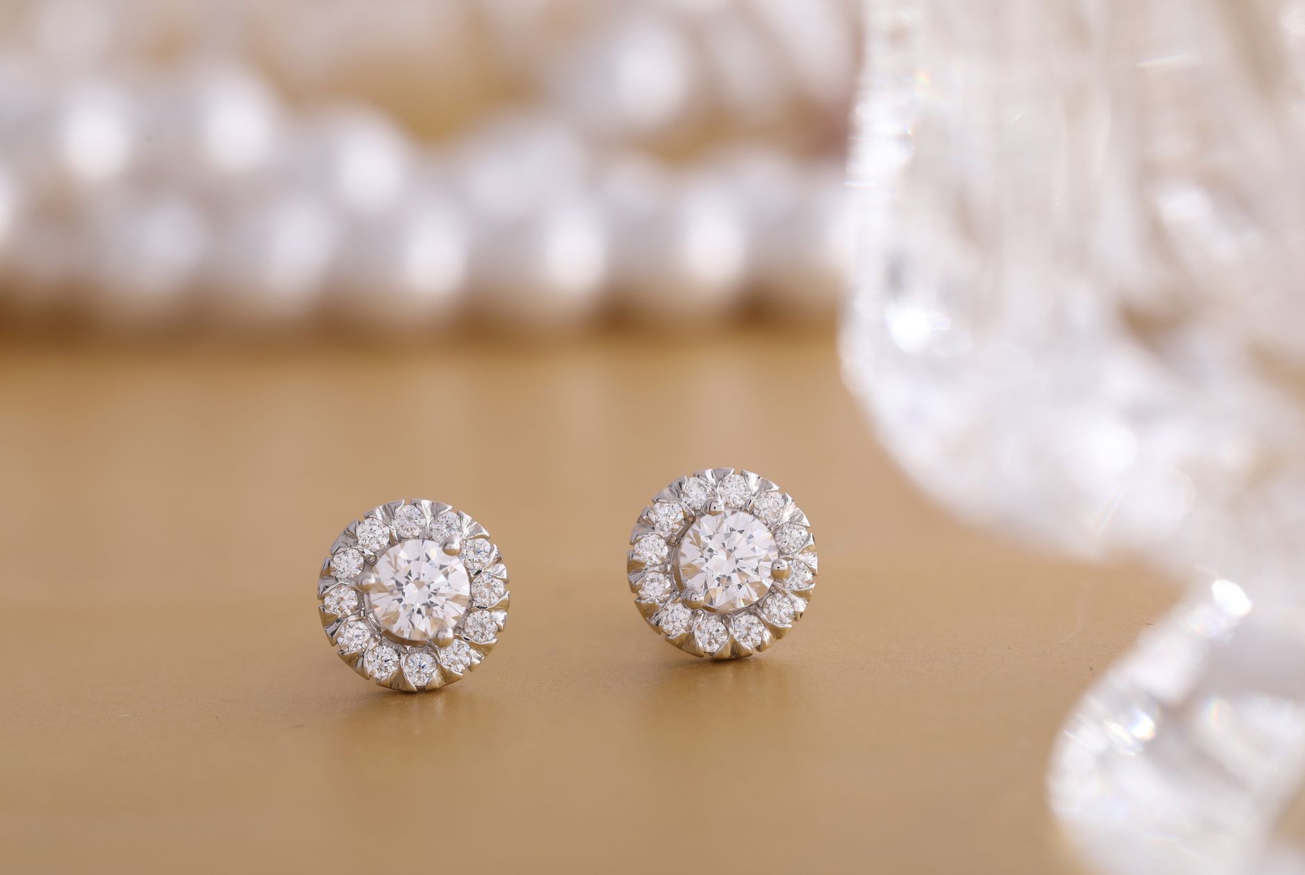 Close-up of round diamond earrings on a gold background, showcasing luxury and elegance.