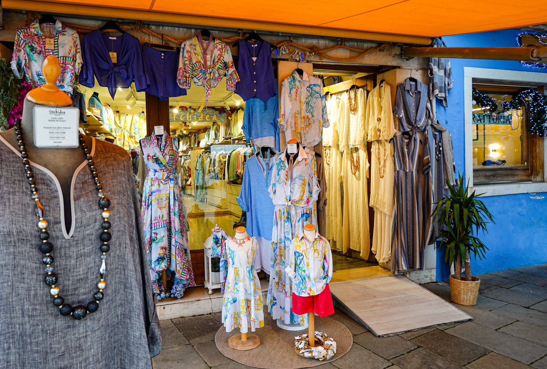 Explore a colorful Italian boutique with stylish dresses and vibrant fabrics on display.