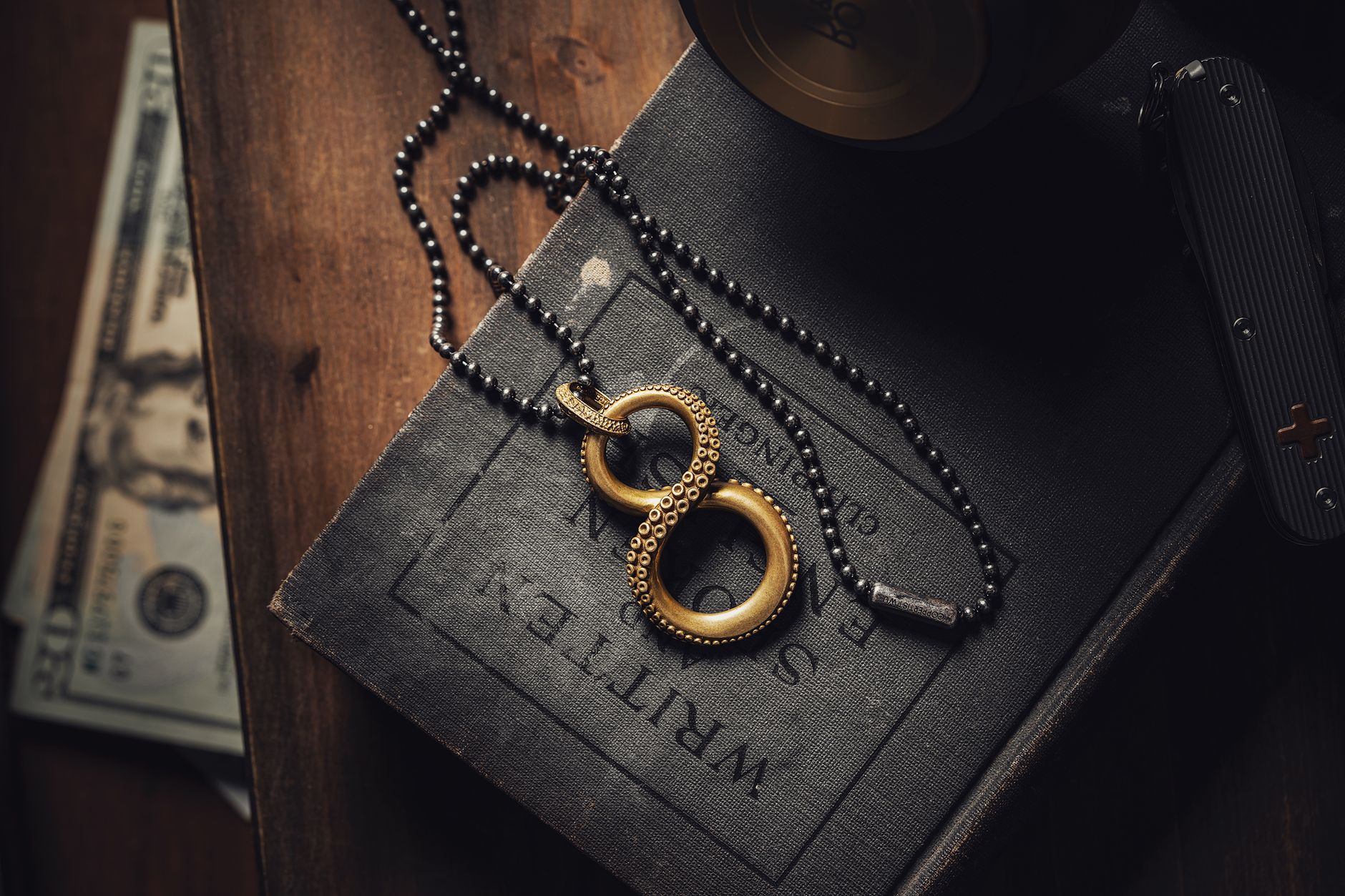 Stylish brass octopus pendant over a vintage book with scattered currency.