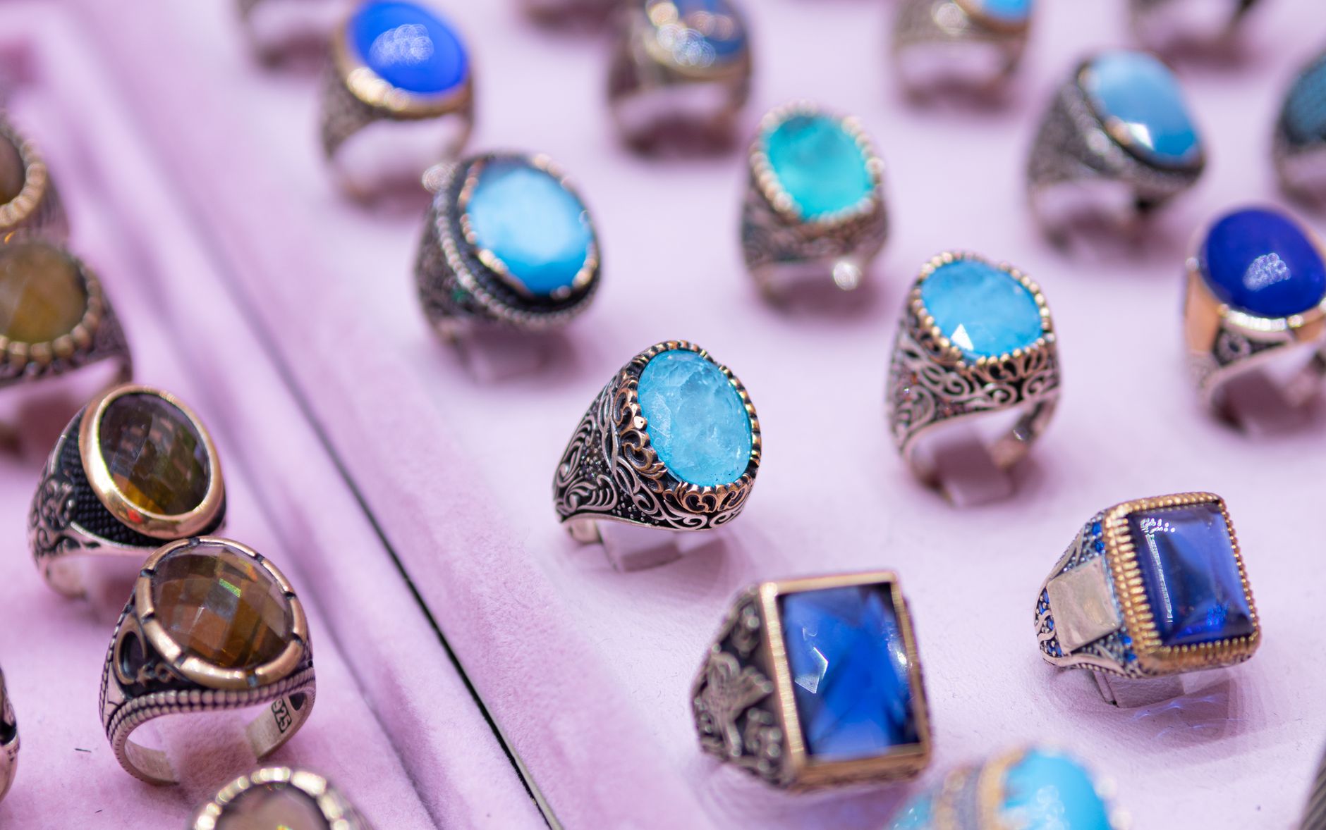 Close-up of beautifully crafted gemstone rings set in intricate silver designs on a soft background.