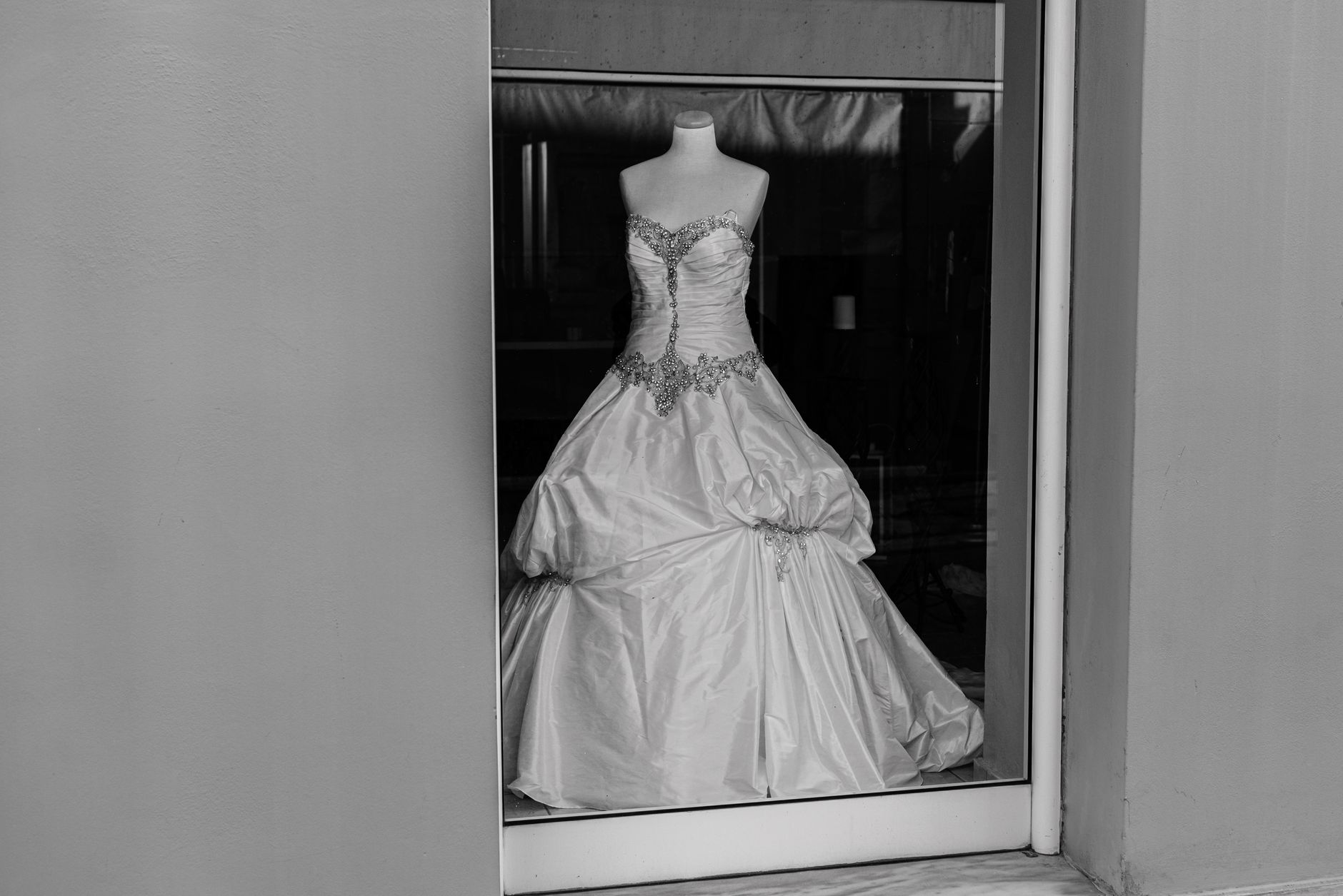 A stylish monochrome shot of a wedding dress on a mannequin in a boutique window.