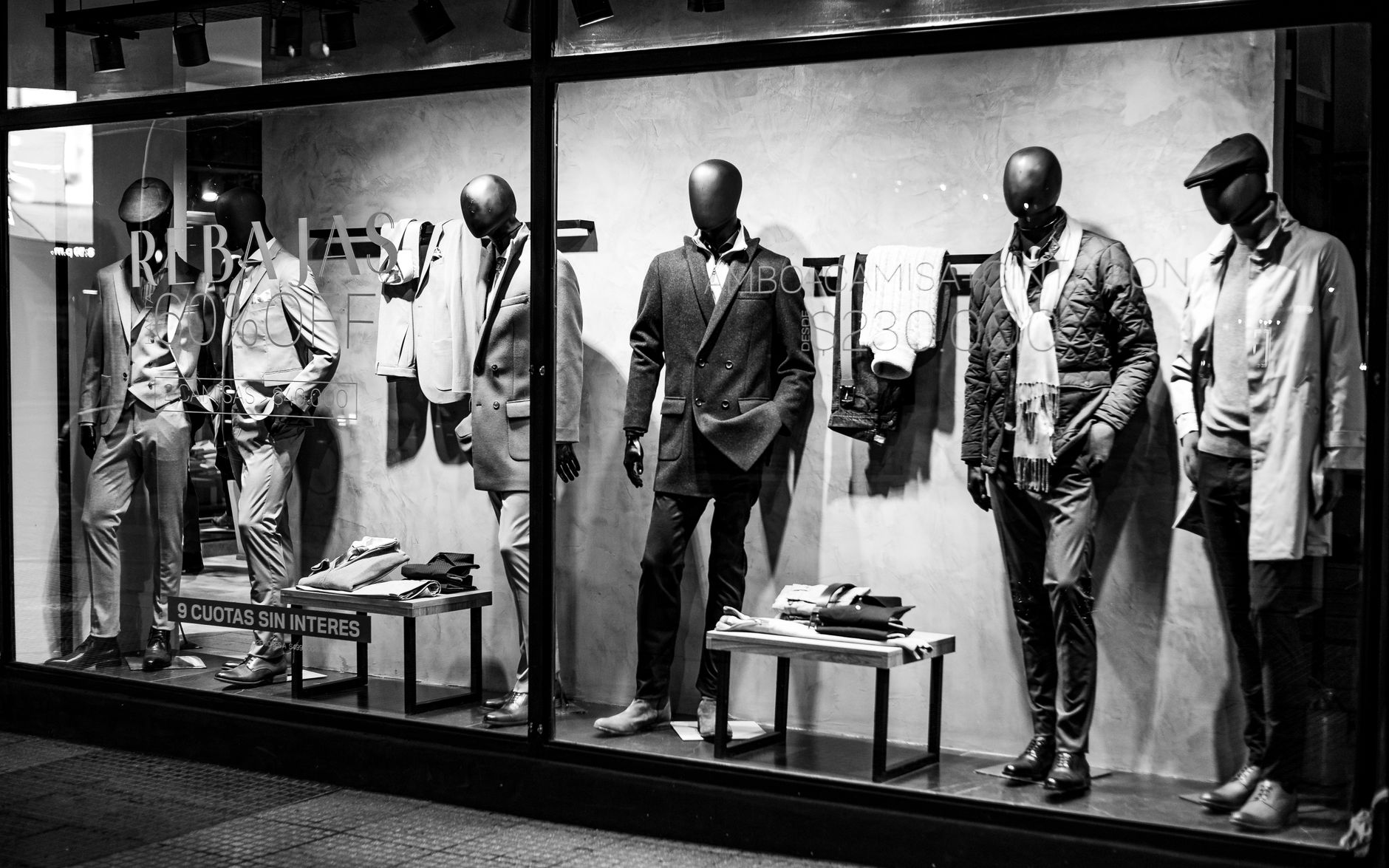 Black and white photo of elegant male mannequins in a clothing store window, Bahía Blanca.