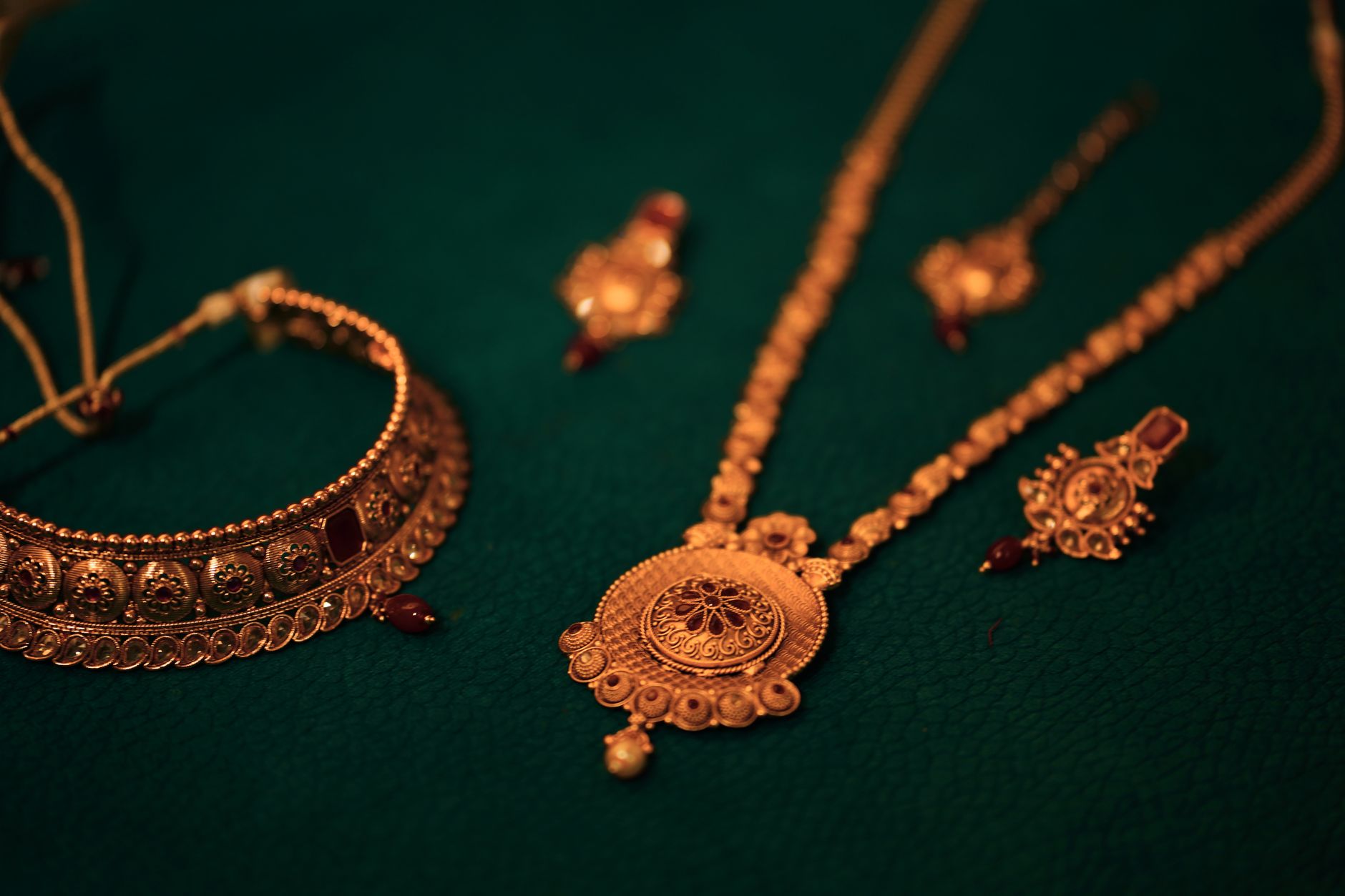 A stunning set of gold jewelry featuring a necklace and earrings on a textured green background.