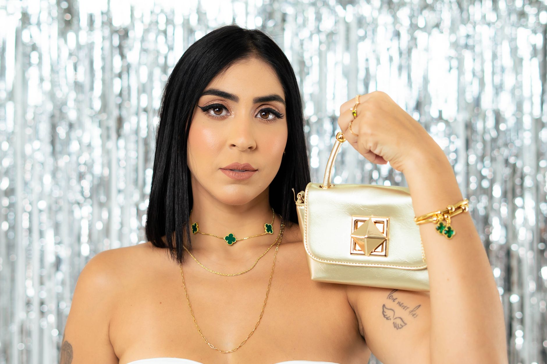 Stylish woman showcasing a chic handbag with silver sequined backdrop.