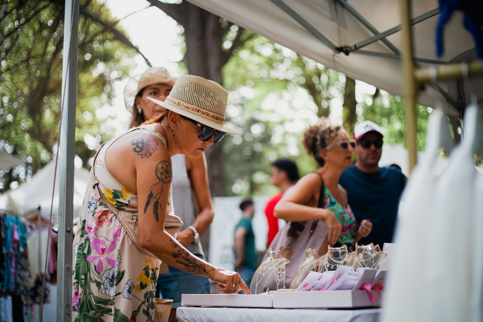 Women browsing at an outdoor street market, vibrant summer setting.
