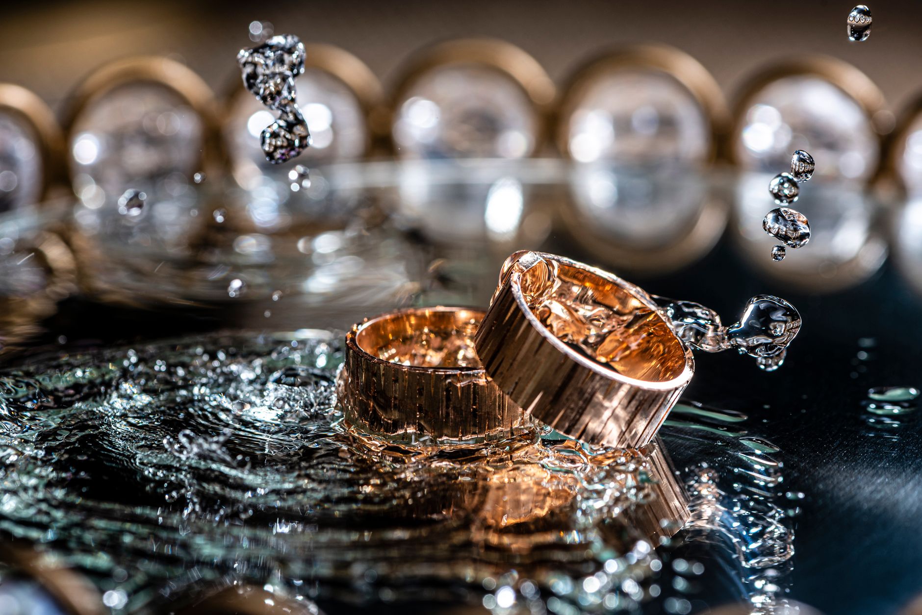 Close-up of gold rings with water splashes, highlighting luxury and elegance.